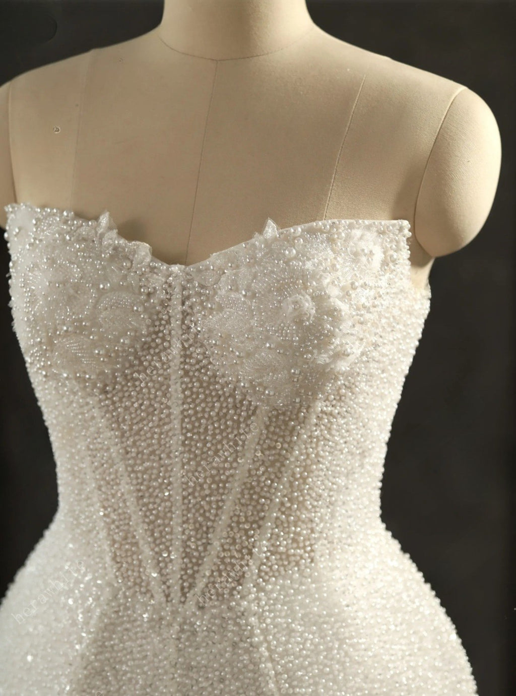 White beaded strapless dress on a mannequin against a black background