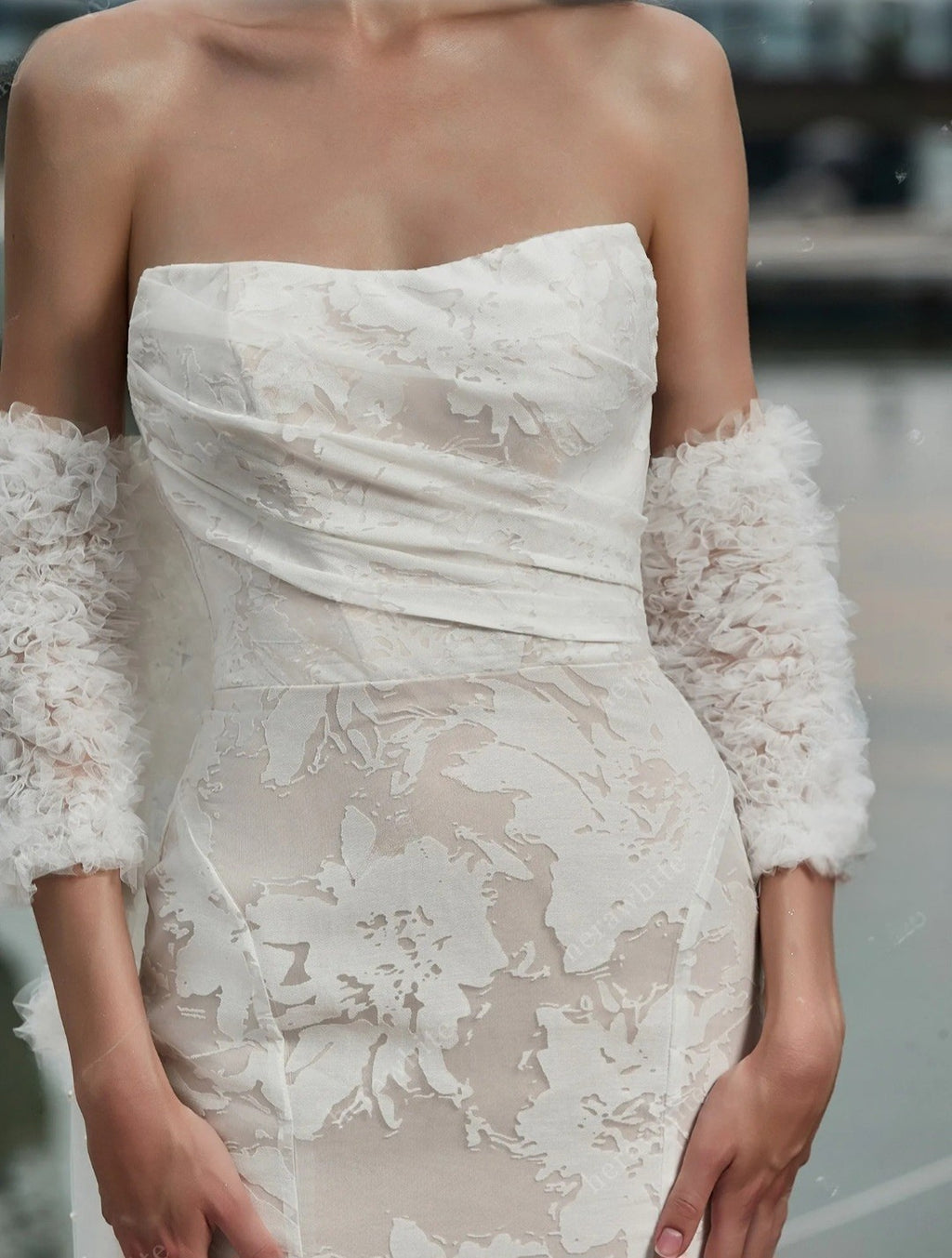 White lace dress with floral patterns and textured sleeves on a blurred background