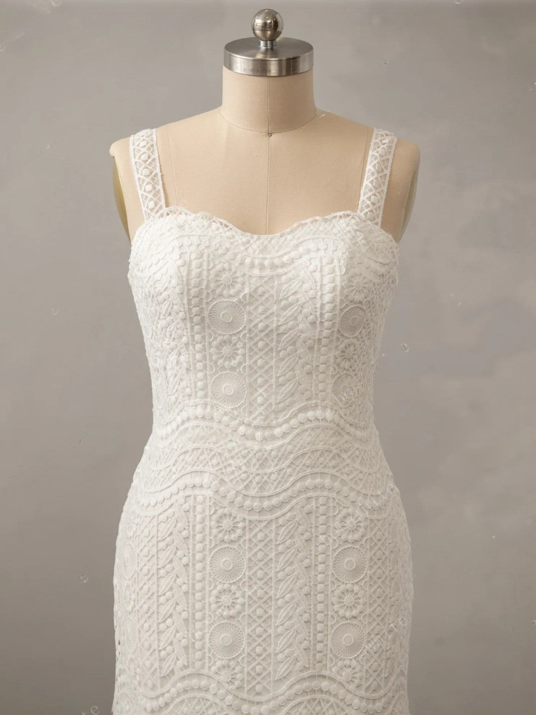 White lace dress on a mannequin against a gray background
