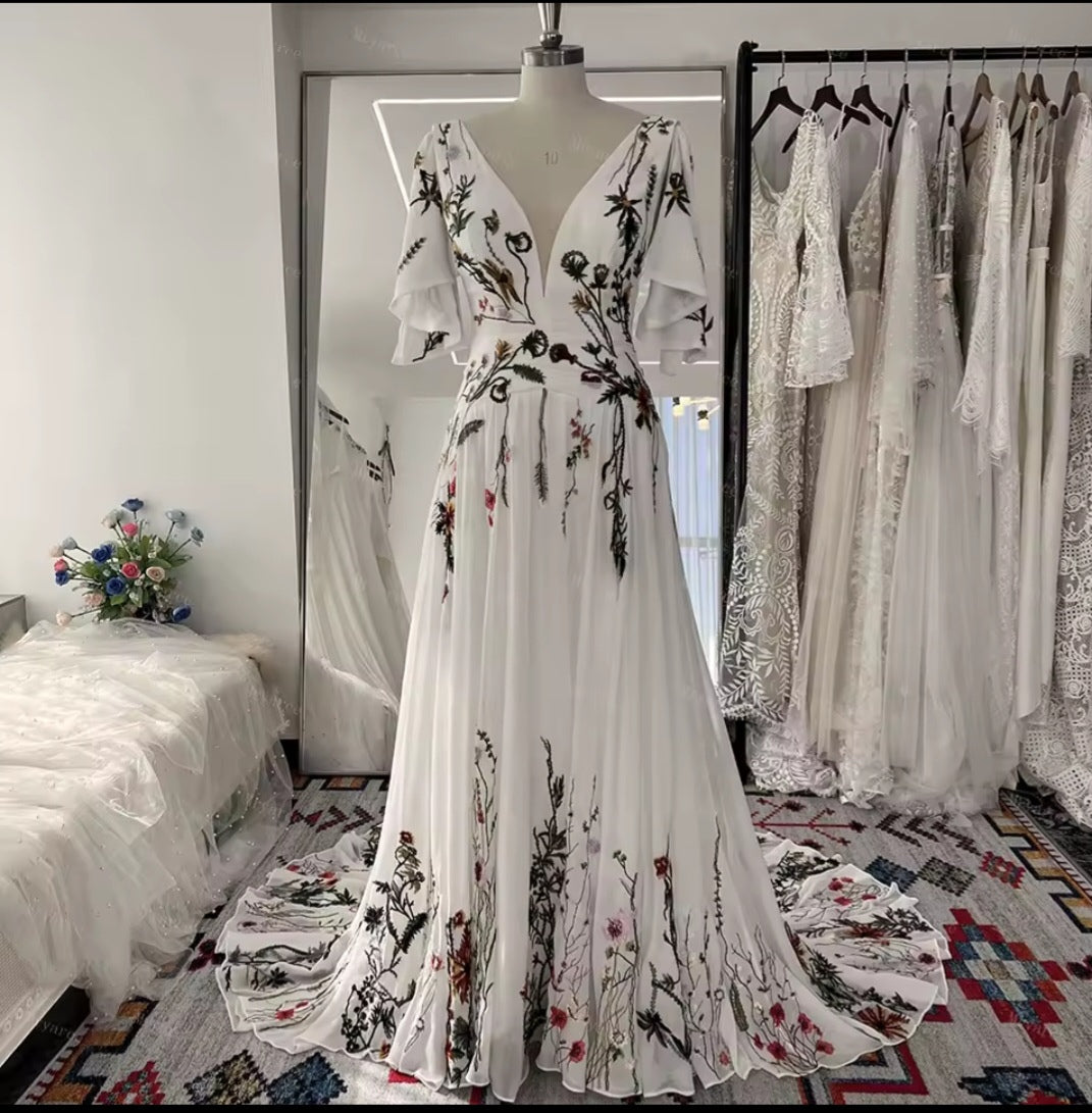 Floral embroidered dress on a mannequin in a room with other dresses and decor.
