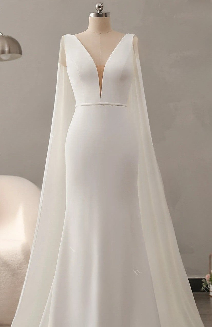 White wedding dress with cape on a mannequin against a neutral background