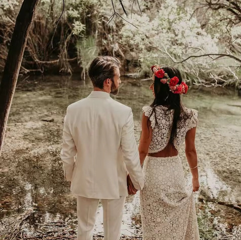 Man and woman holding hands by a river with a natural, forested background