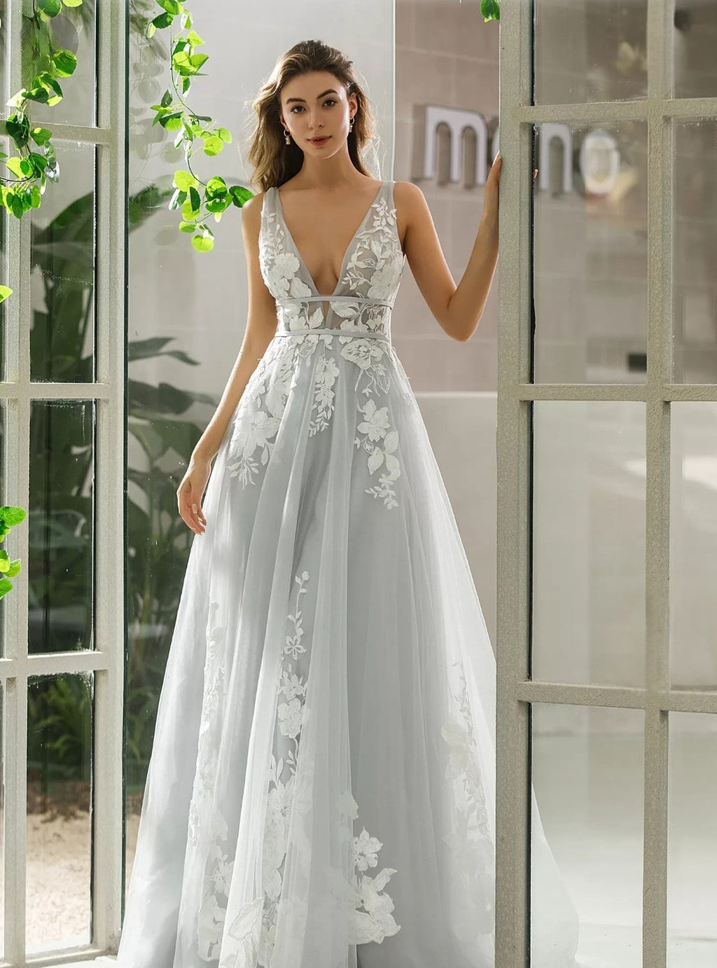 Woman wearing a white lace dress standing indoors with a neutral background