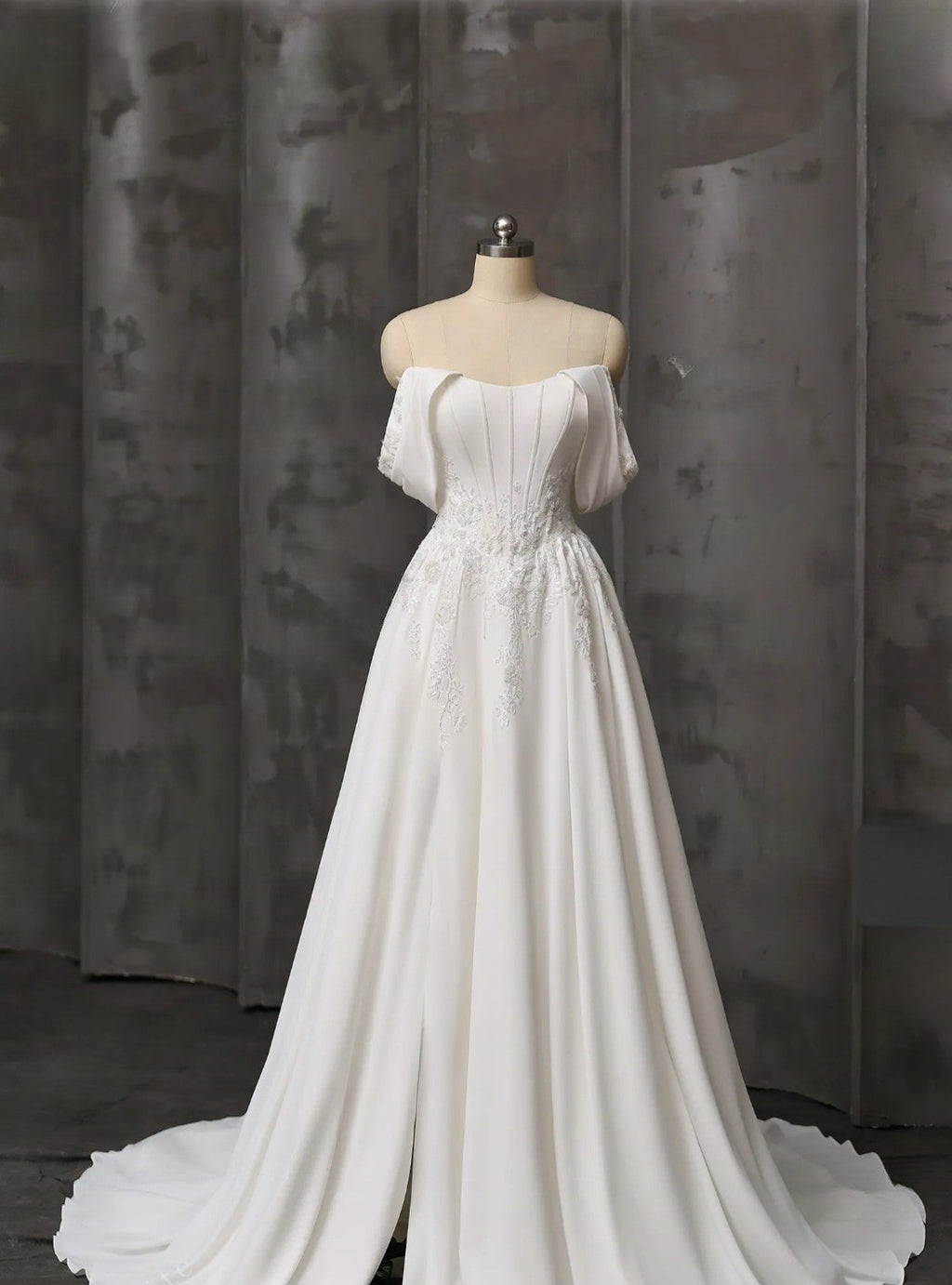 White wedding dress on a mannequin against a dark curtain background