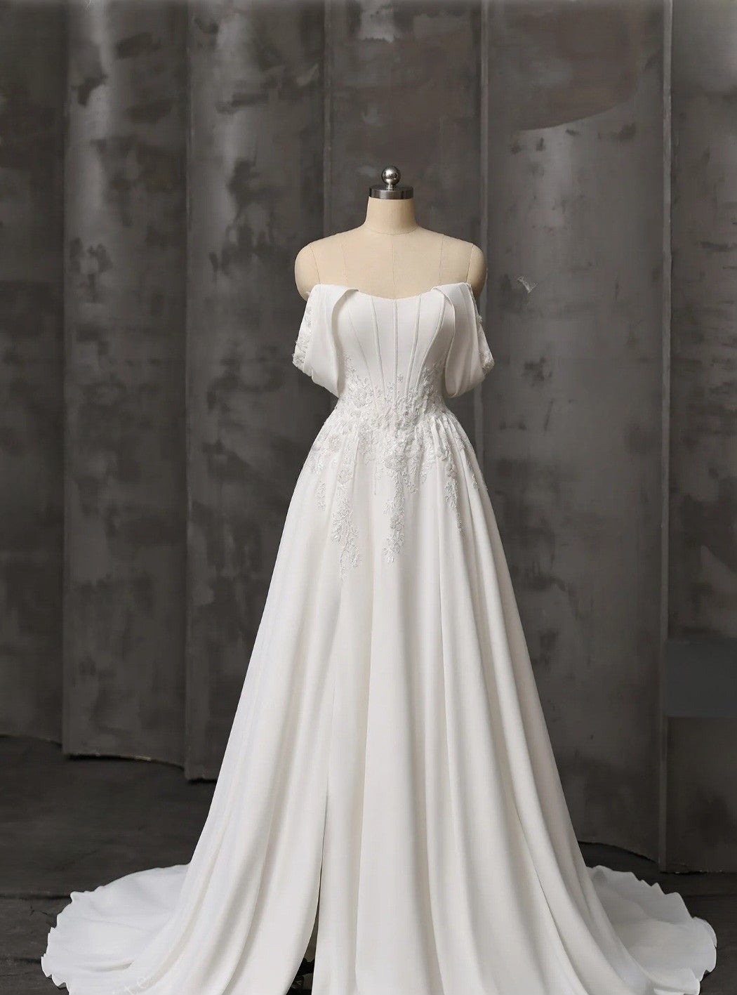 White wedding dress on a mannequin against a dark curtain background