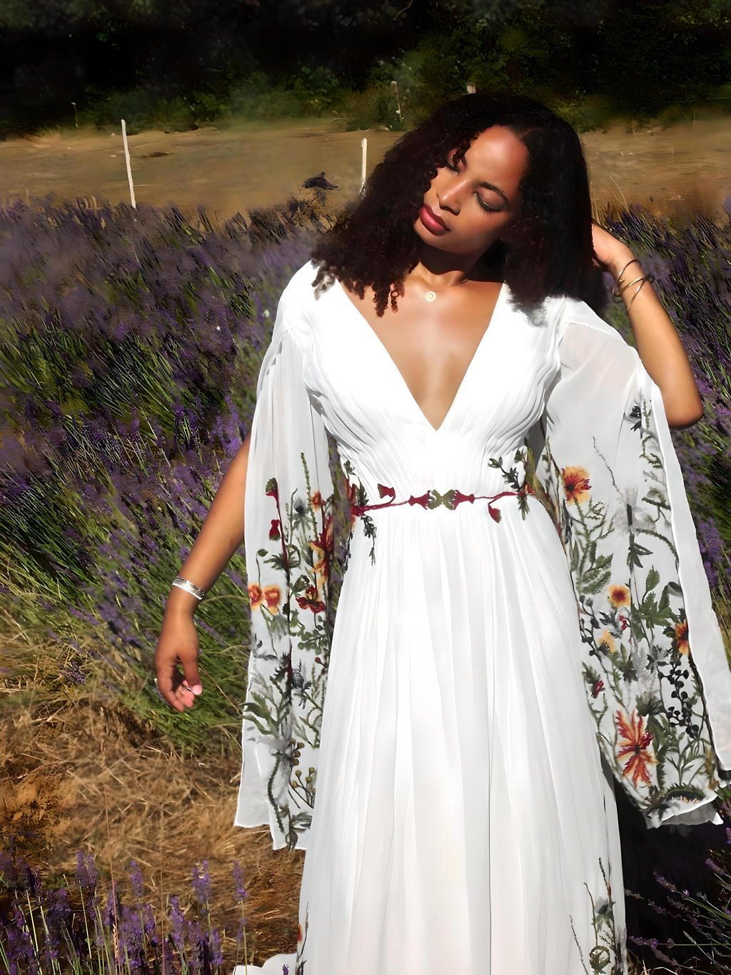 Woman in a white dress with floral embroidery standing in a lavender field.