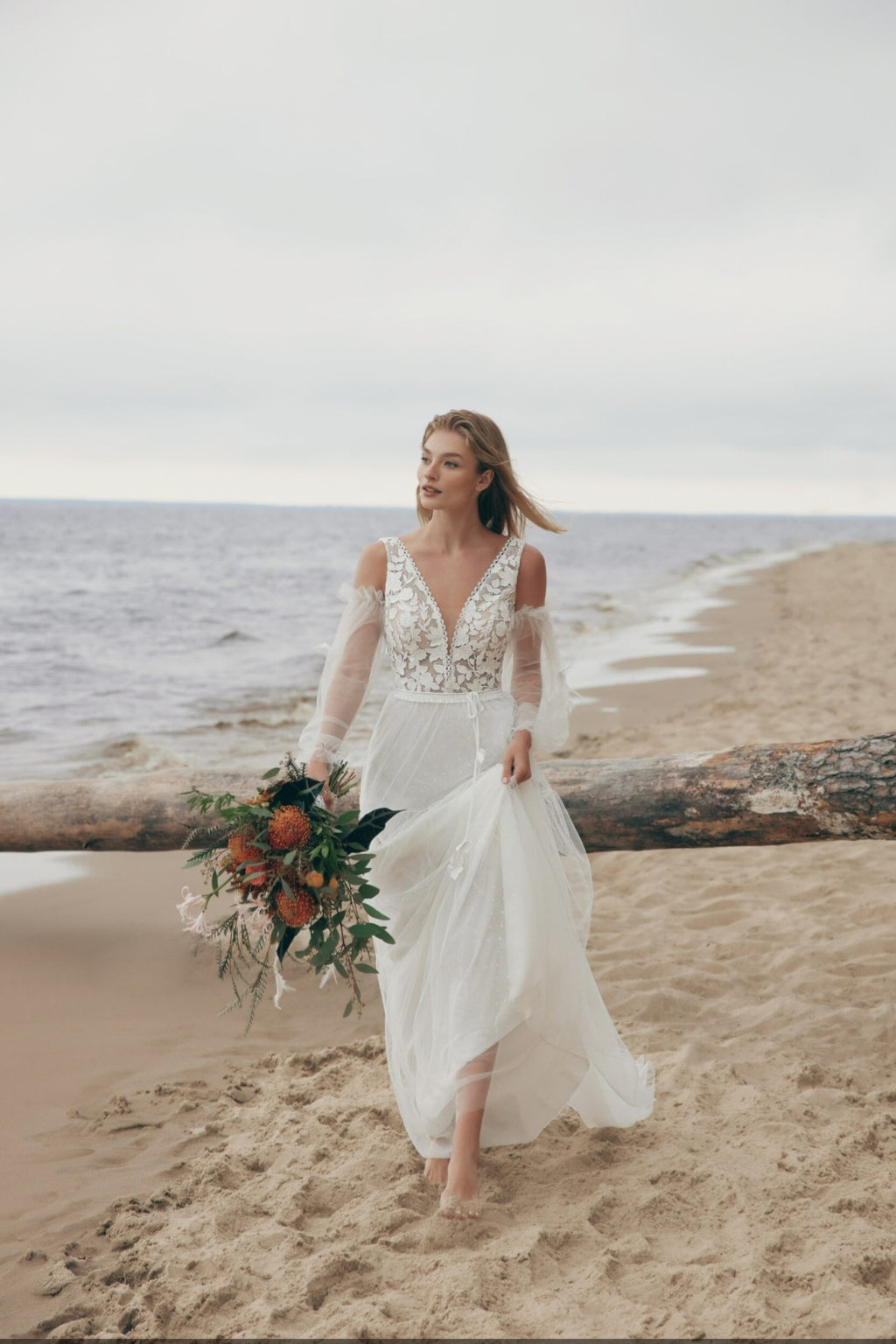 Woman in a wedding dress holding a bouquet on a beach