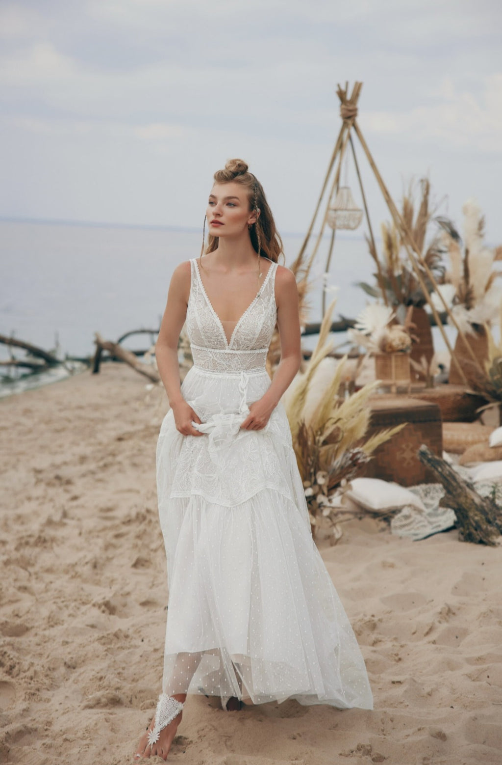Woman in a white dress standing on a beach with decorative elements.