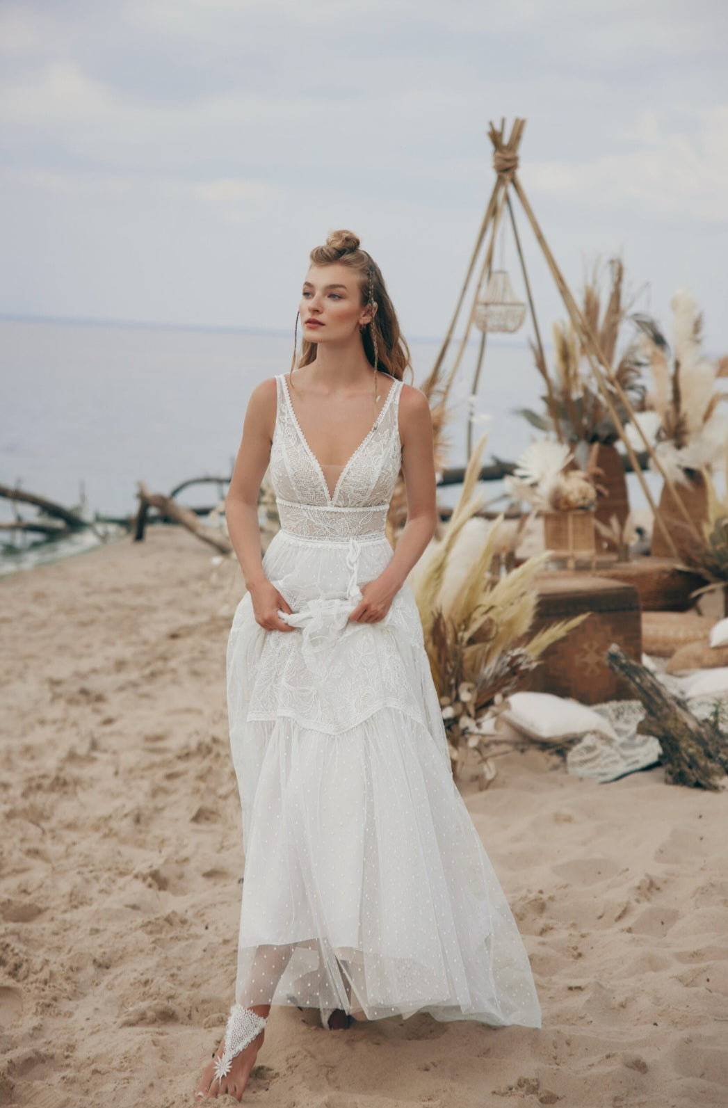 Woman in a white dress standing on a beach with decorative elements.