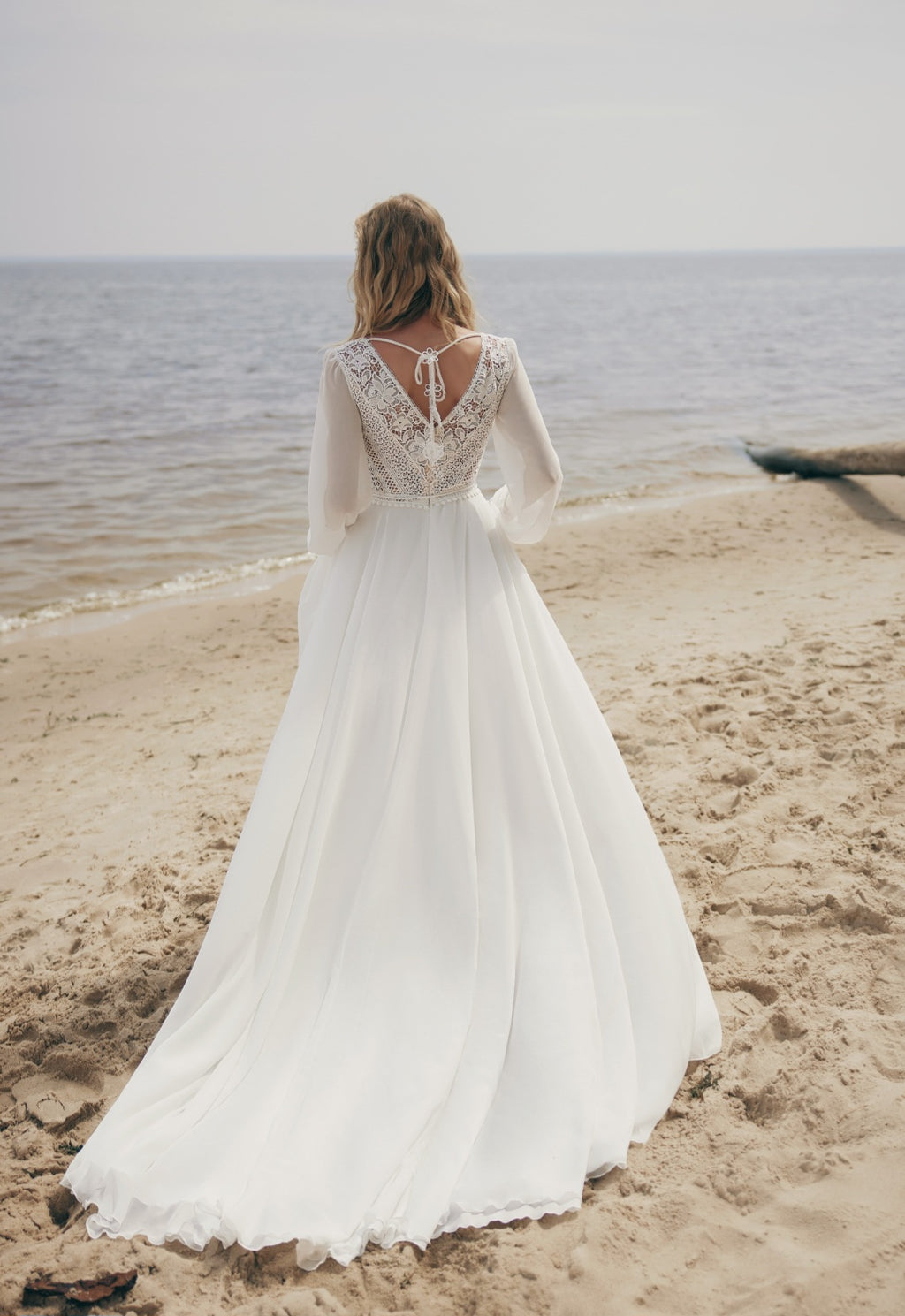 Woman in a white wedding dress standing on a beach with ocean view