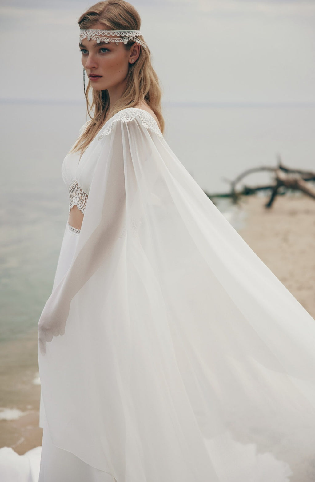 Woman in a white dress with a sheer overlay on a beach