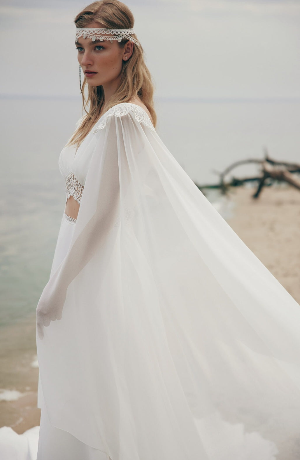 Woman in a white dress with a sheer overlay on a beach