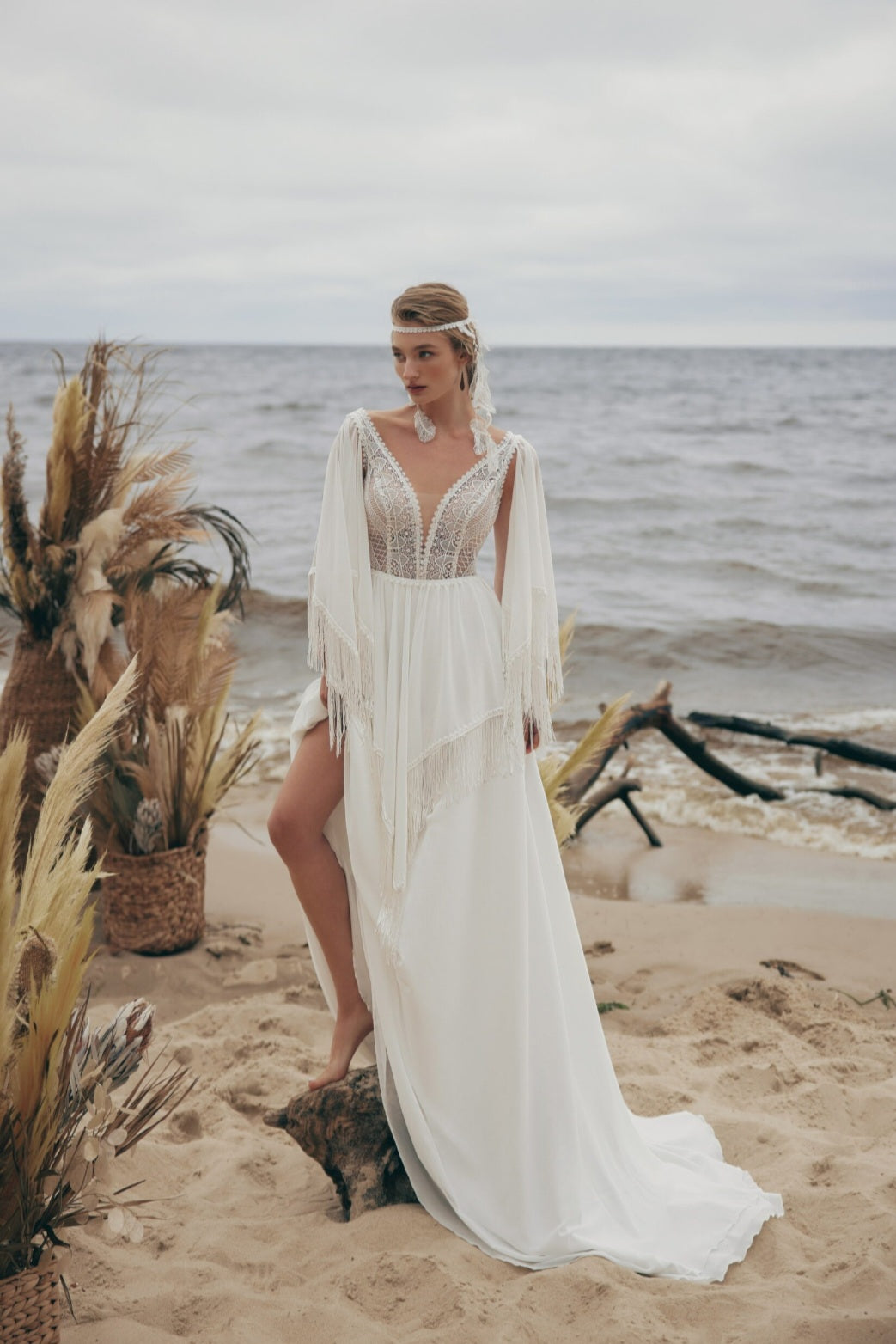 Woman in a white dress standing on a beach with ocean in the background