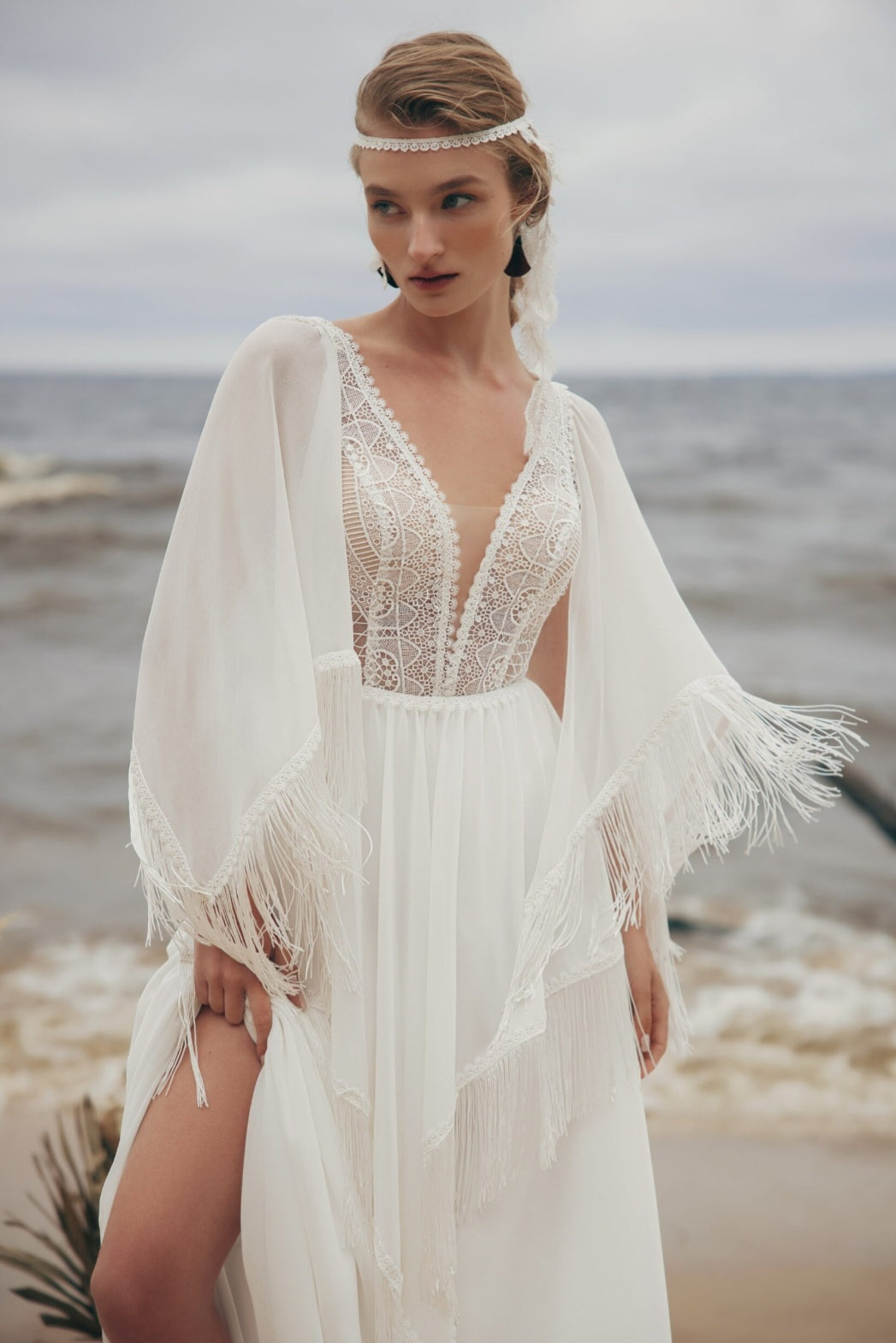 Woman in a white lace dress with a headband on a beach