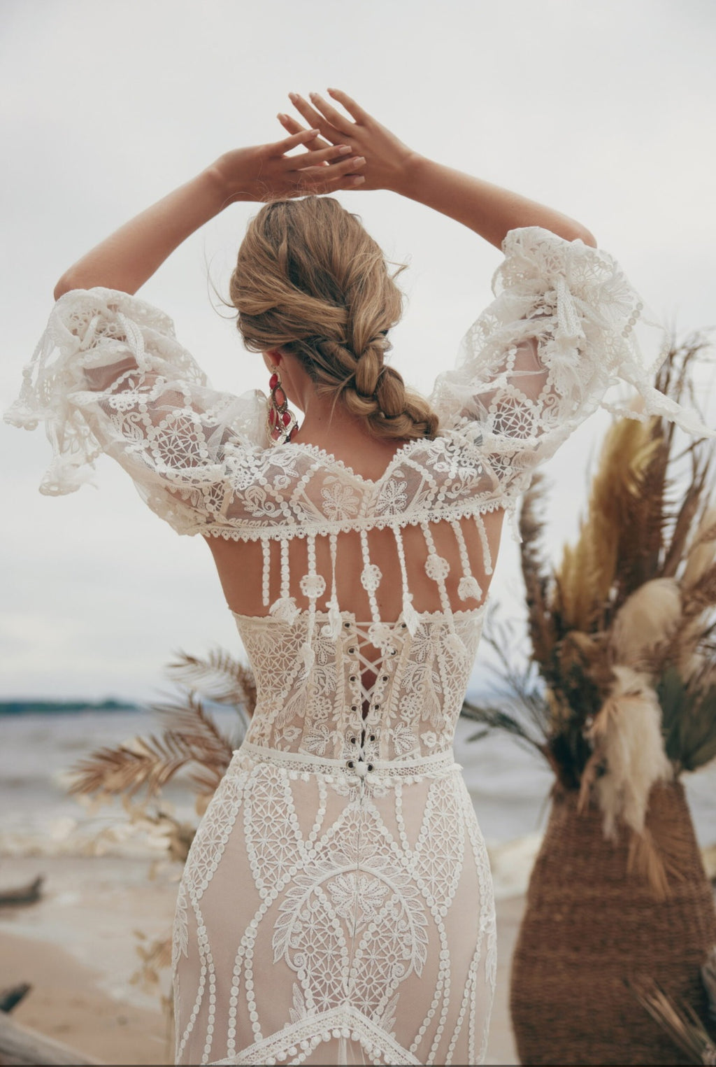 Woman in a lace dress with a beach and palm leaves in the background