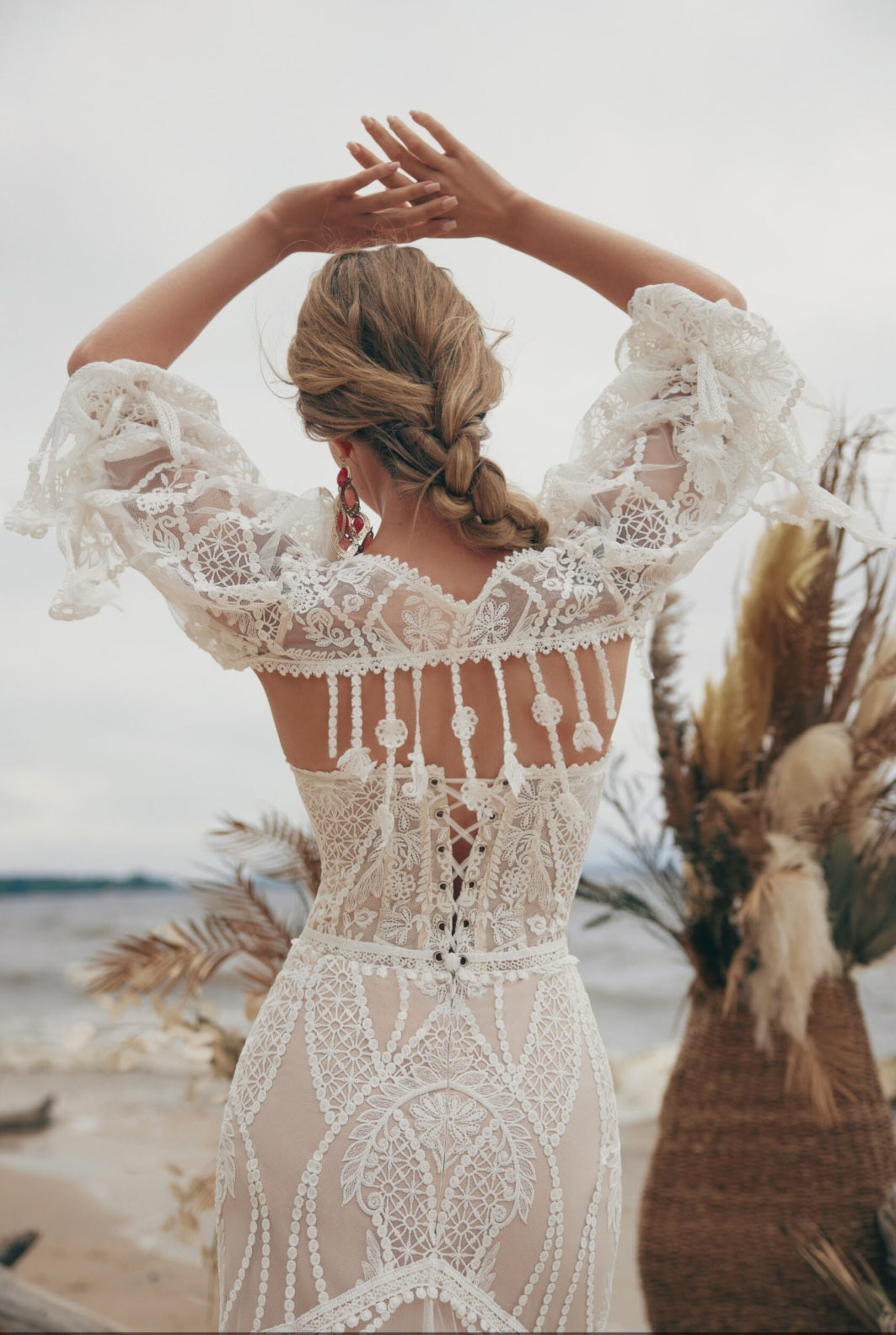 Woman in a lace dress with a beach and palm leaves in the background