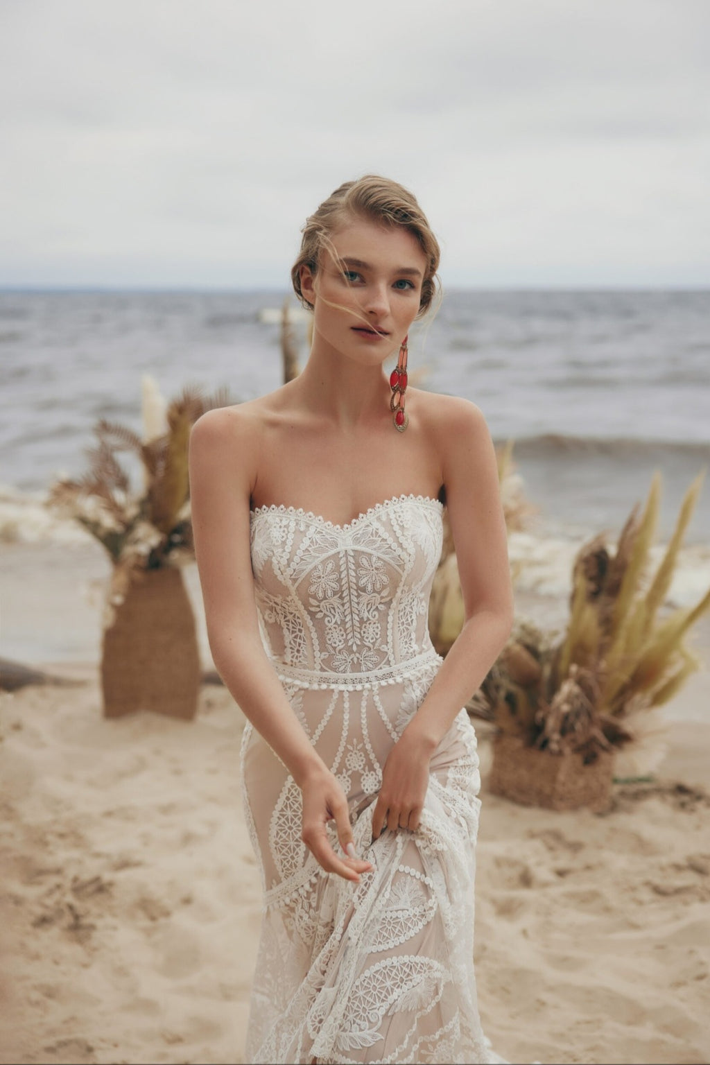 Woman in a lace dress standing on a beach with ocean view
