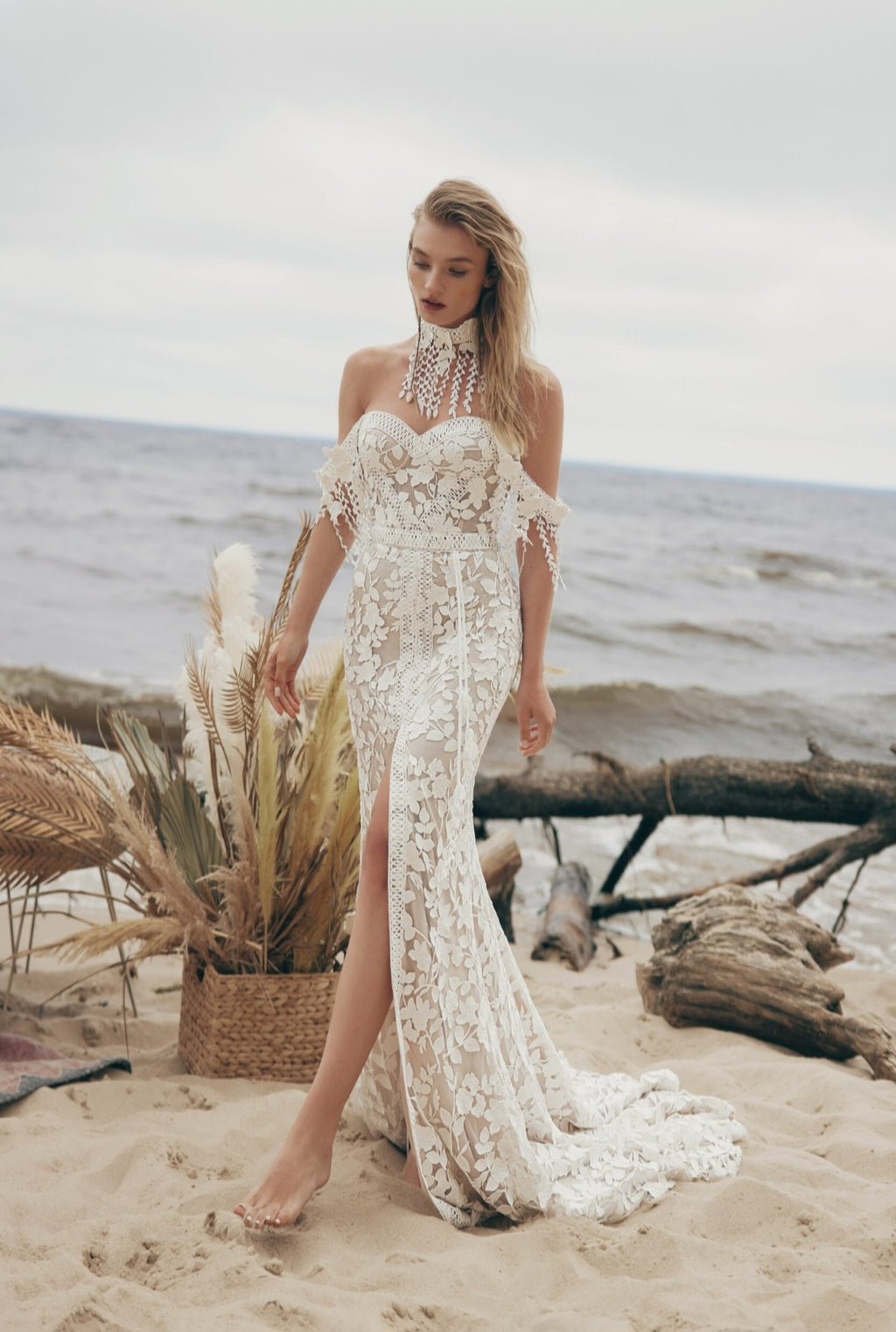 Woman in a lace dress standing on a beach with ocean in the background