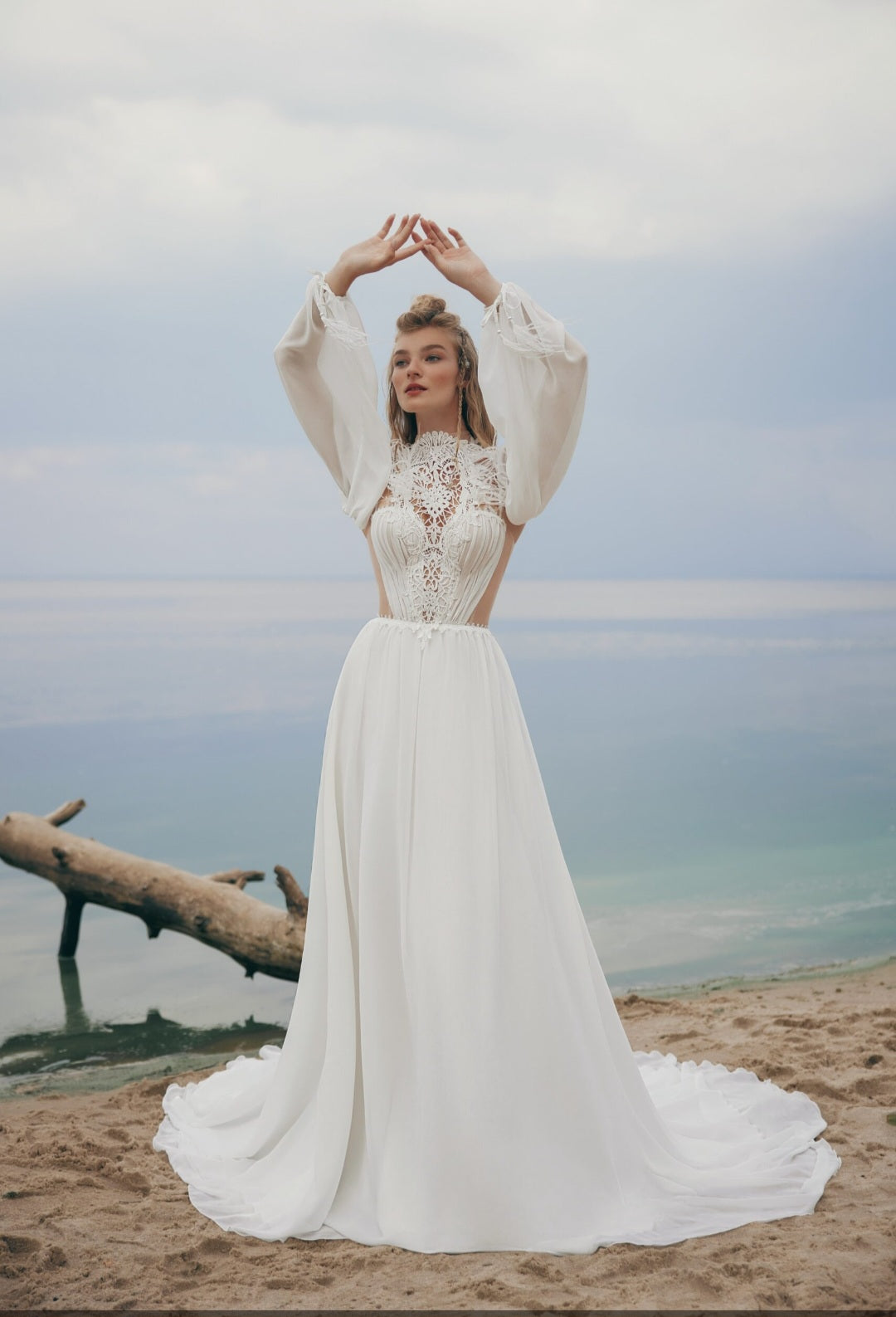 Woman in a white wedding dress standing on a beach with a scenic background