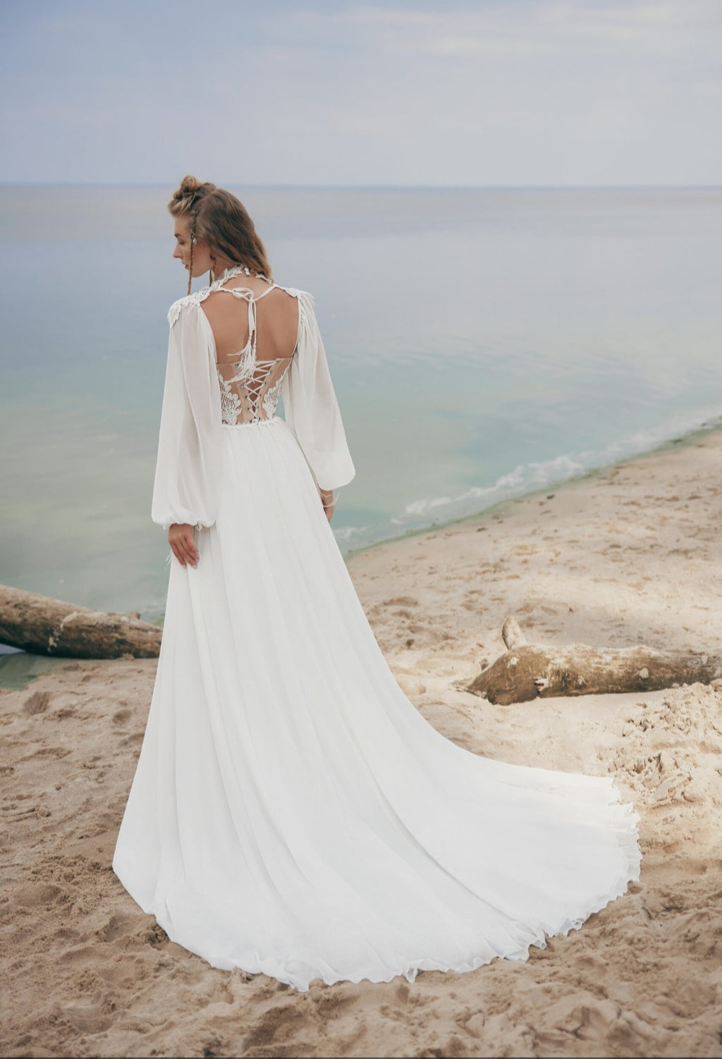 Woman in a white dress standing on a beach with ocean view