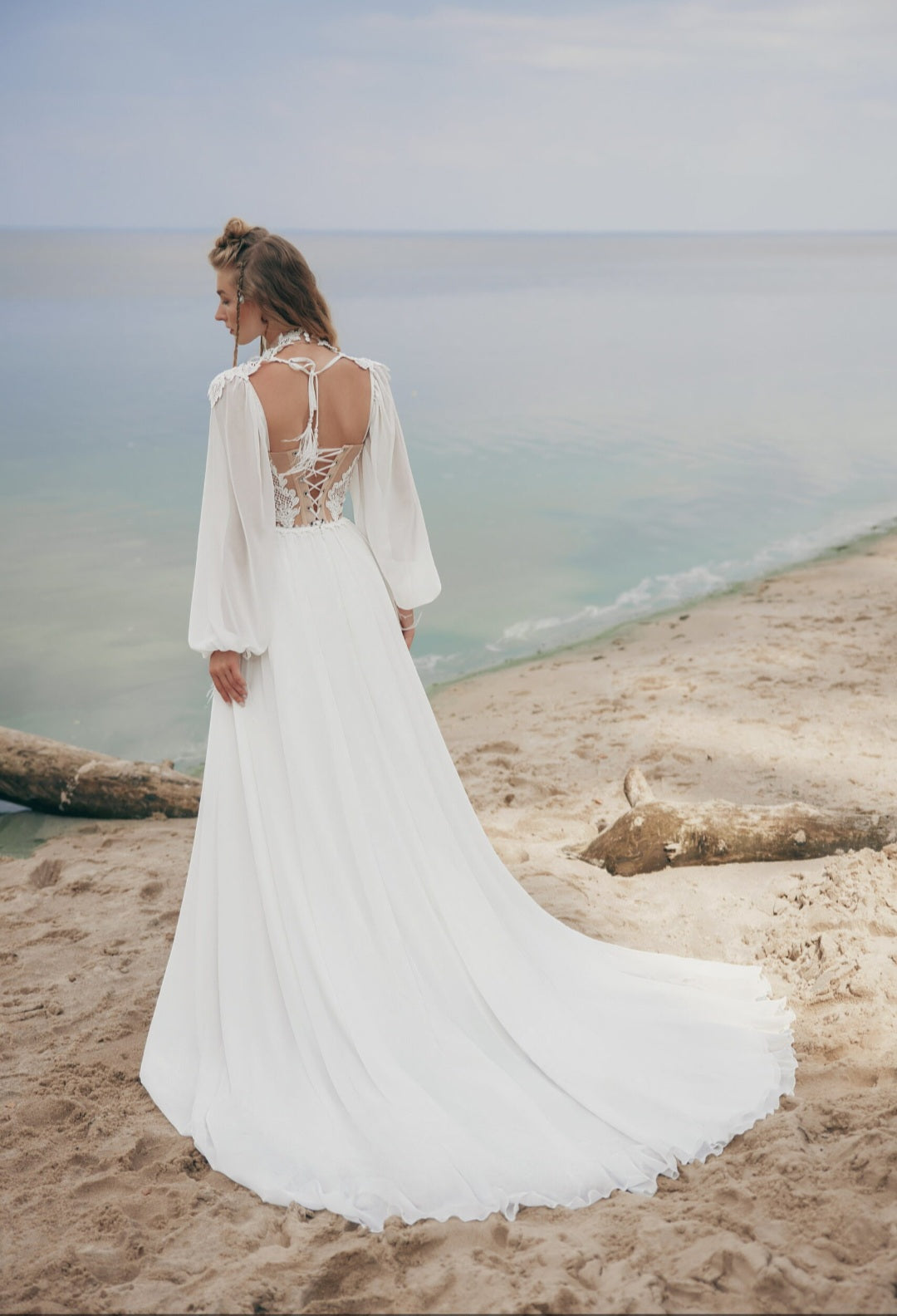 Woman in a white dress standing on a beach with ocean view
