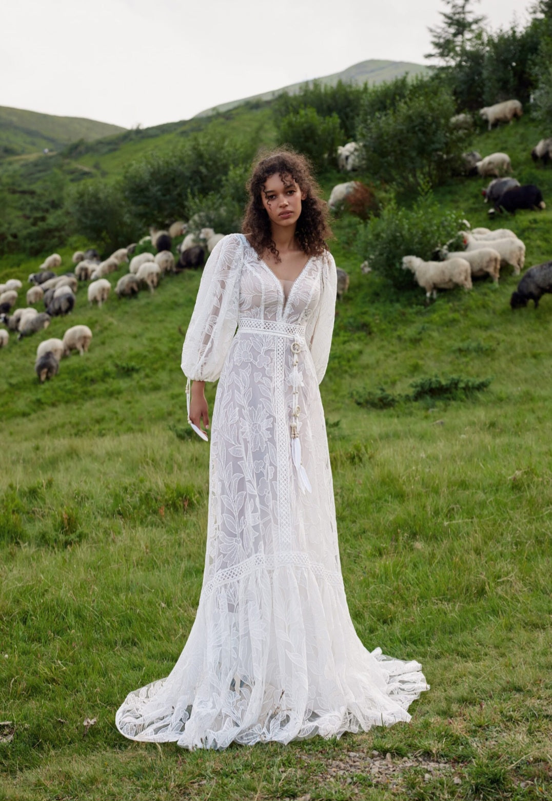 Woman in a white dress standing in a field with sheep