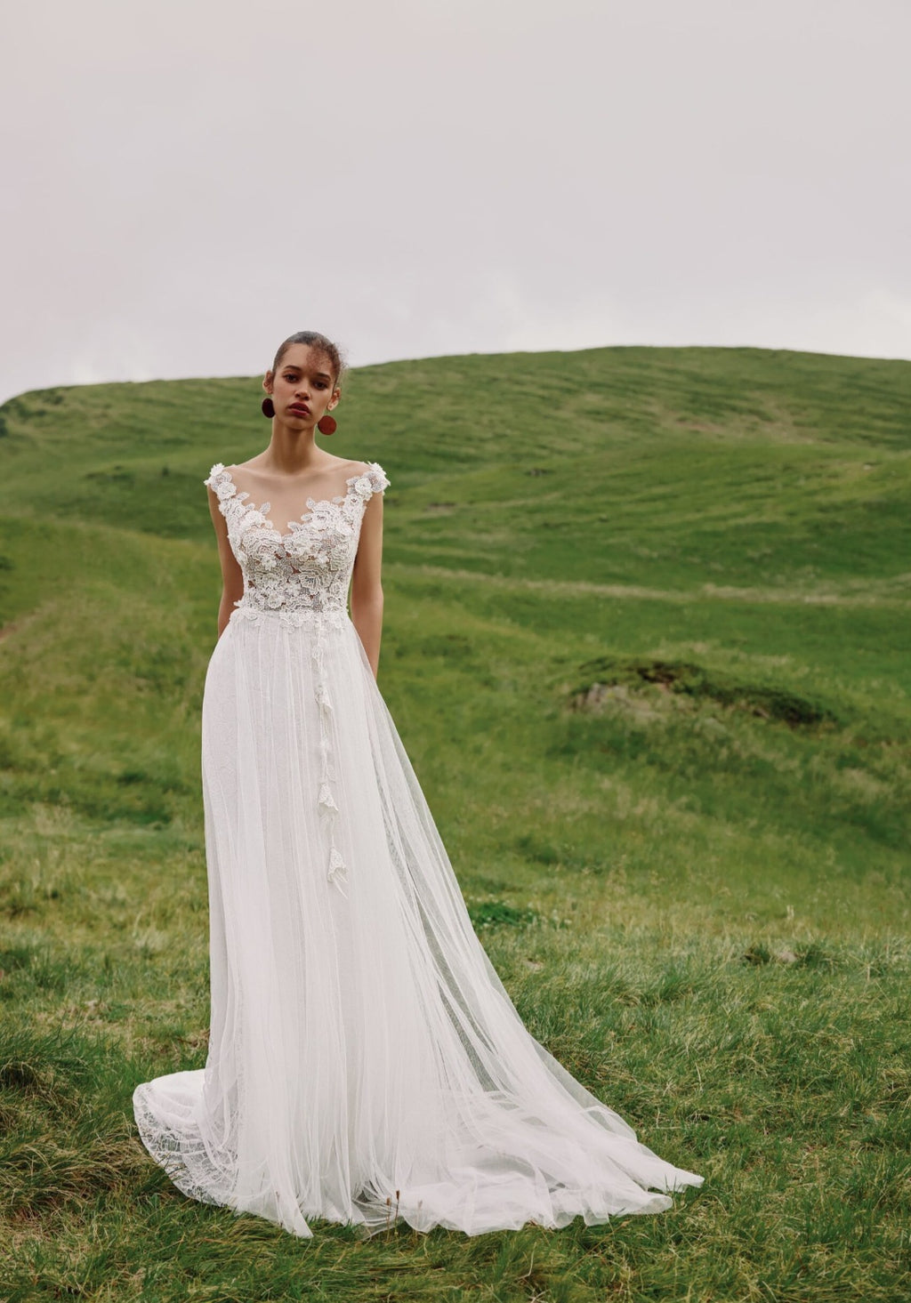 Woman in a white wedding dress standing in a grassy field