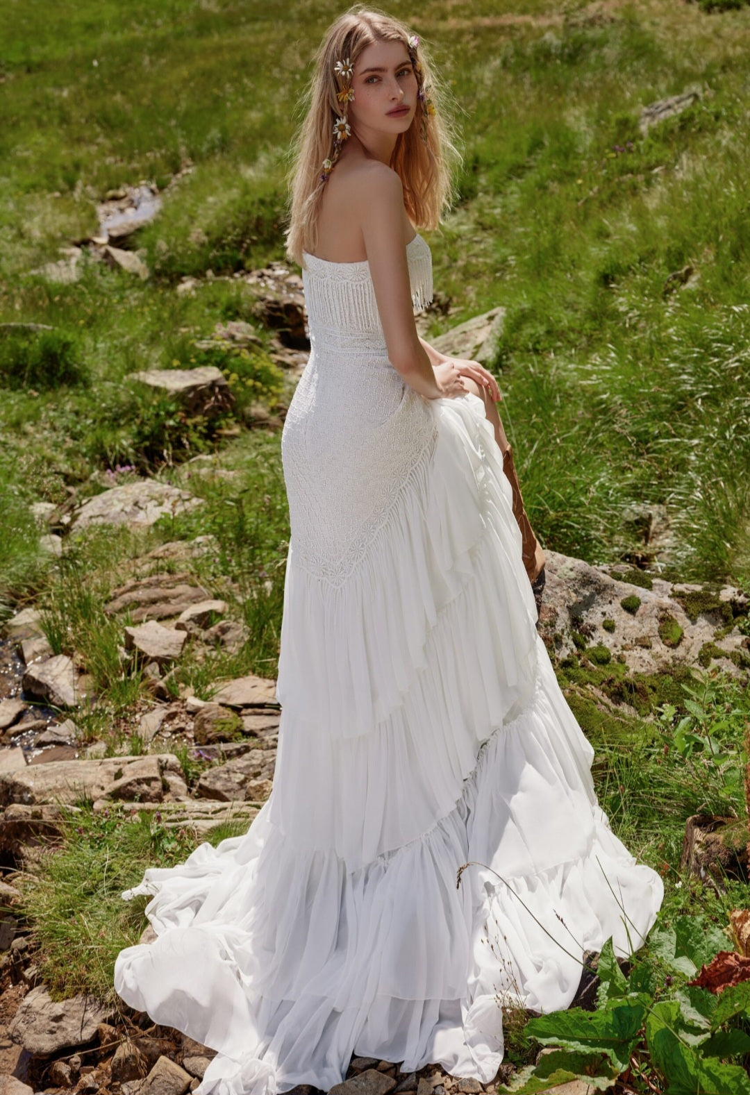 Woman in a white dress standing in a natural setting with greenery