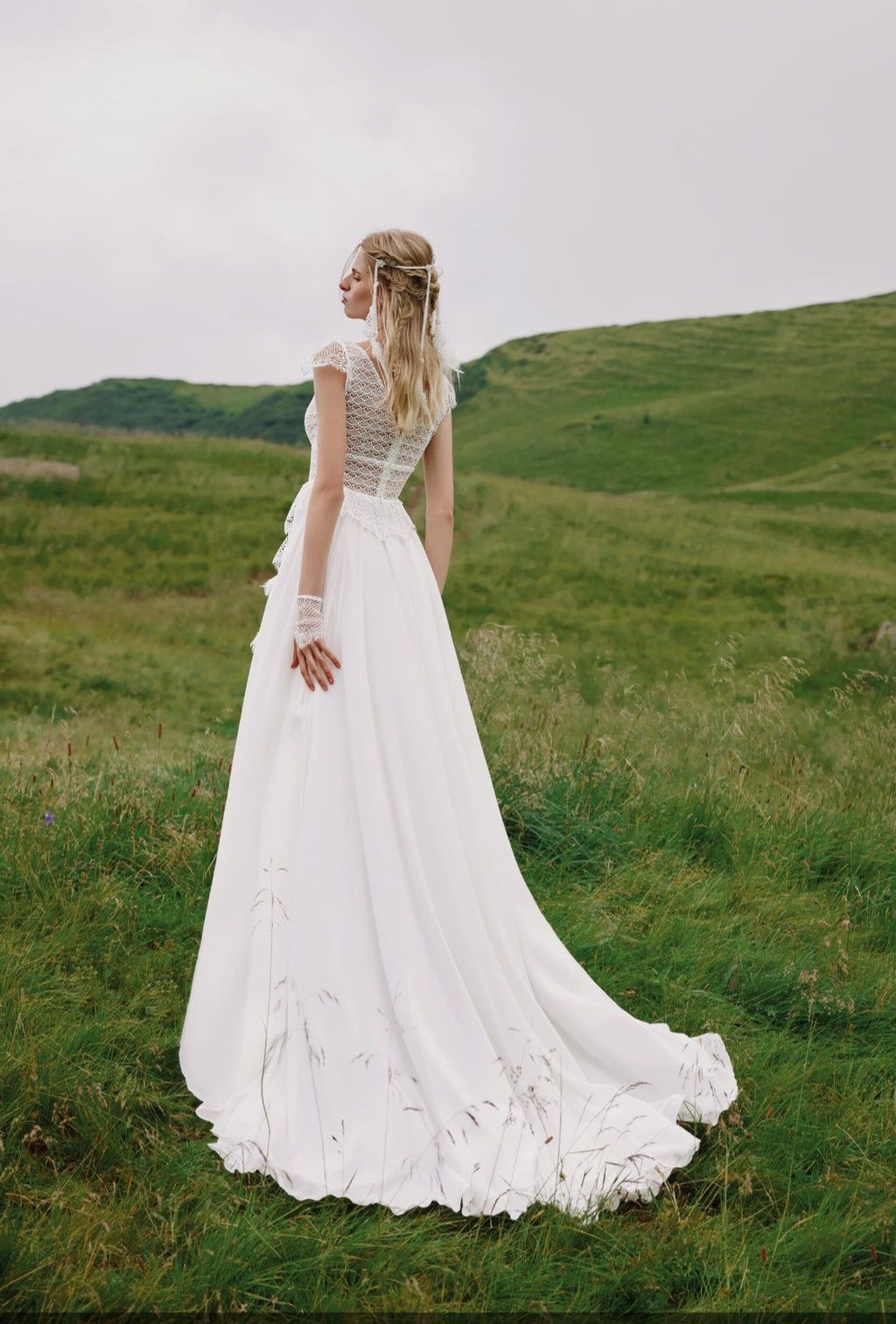Woman in a white wedding dress standing in a grassy field