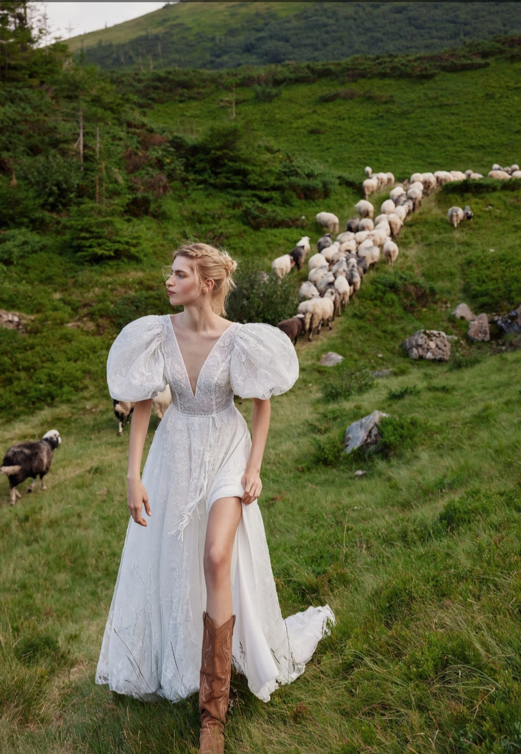 Woman in a white dress standing in a field with sheep