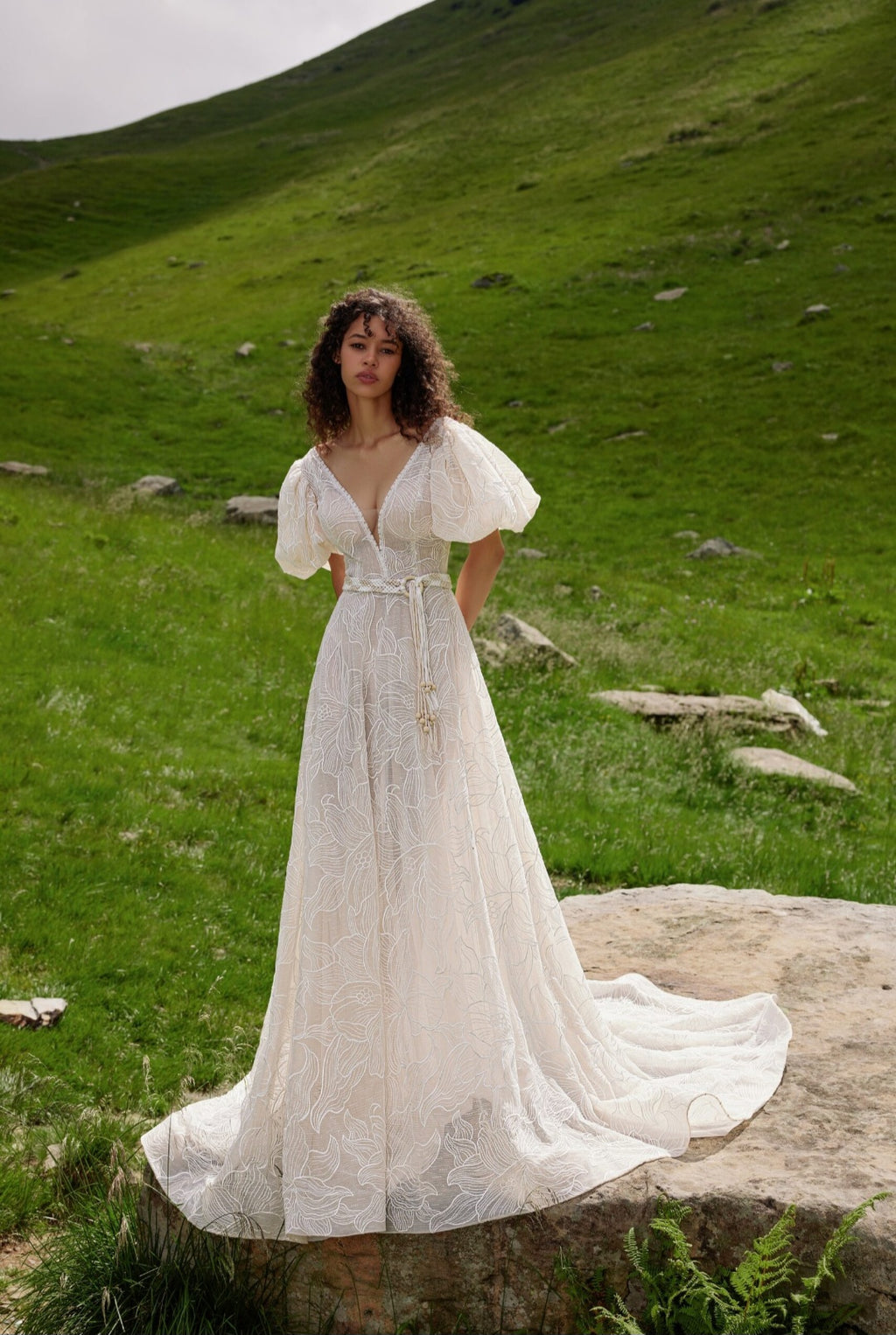 Woman in a white dress standing on a grassy hillside