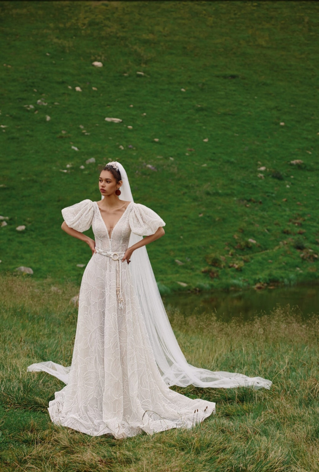 Woman in a white wedding dress standing in a green field