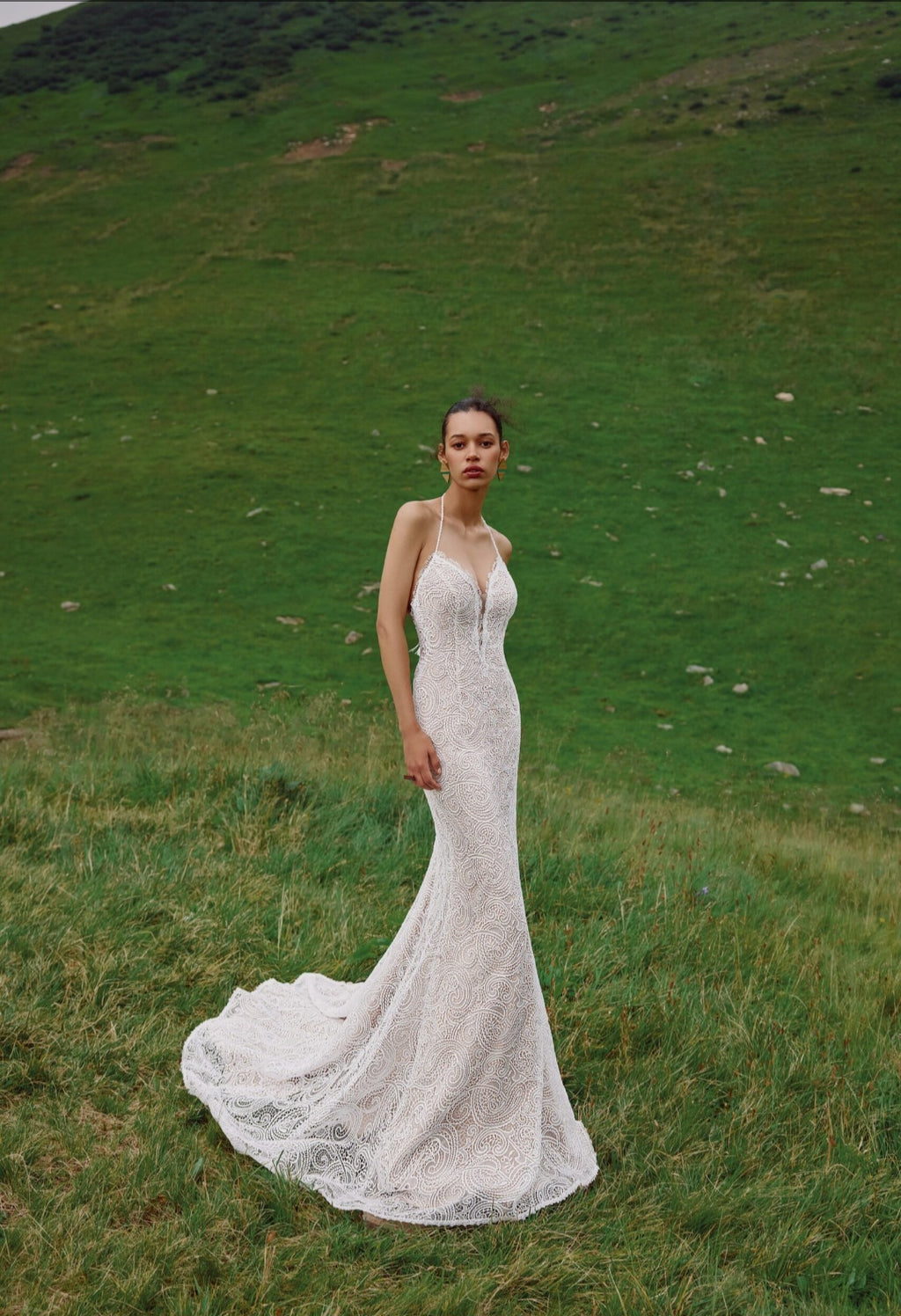 Woman in a white lace wedding dress standing in a grassy field