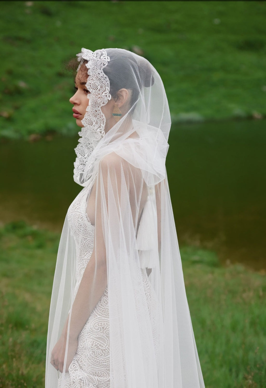 Woman wearing a white lace veil and dress in a natural setting
