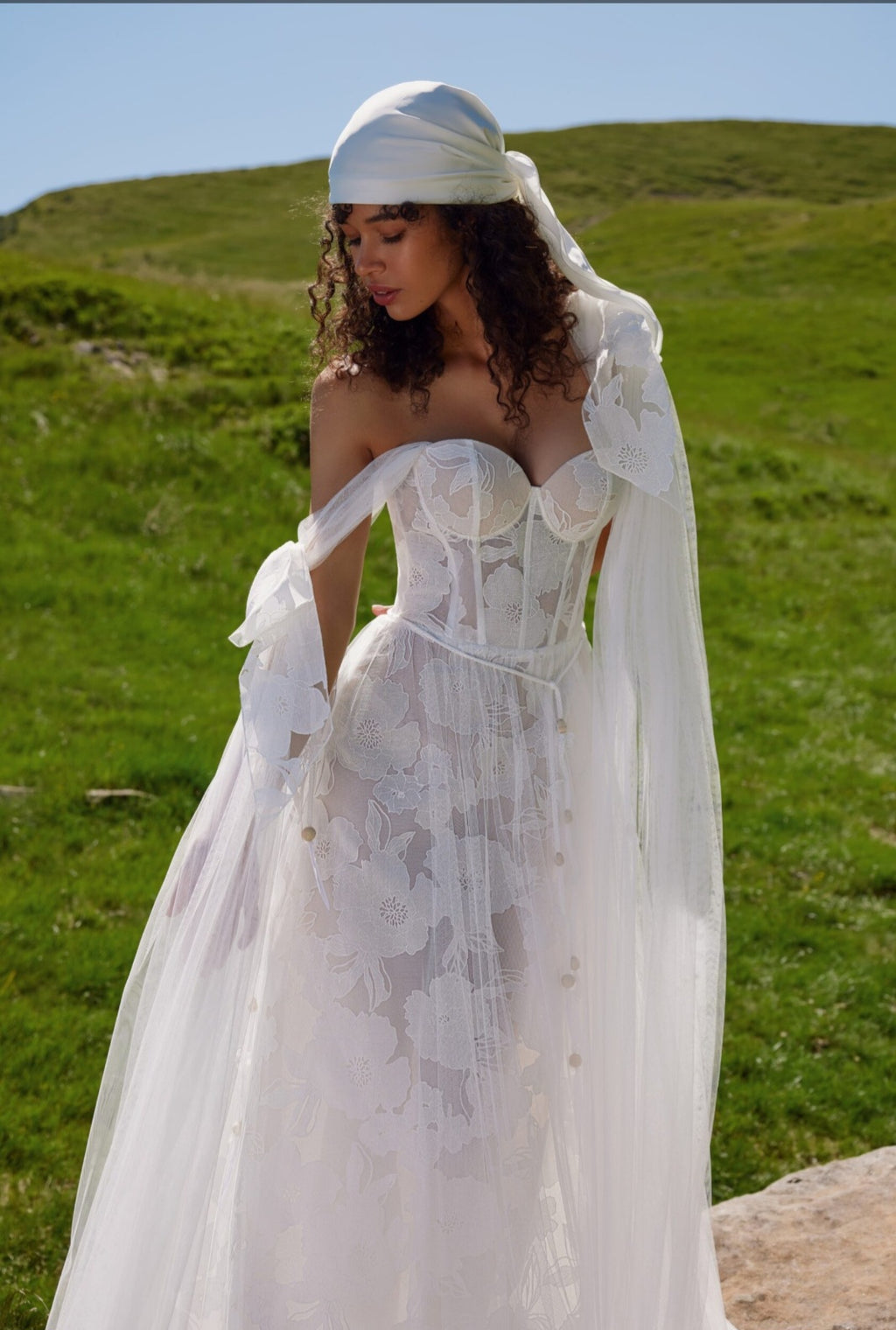 Woman in a white wedding dress standing in a grassy field