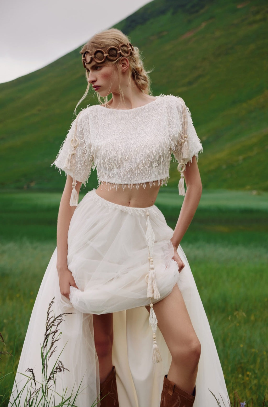 Woman in a white fringe outfit standing in a grassy field