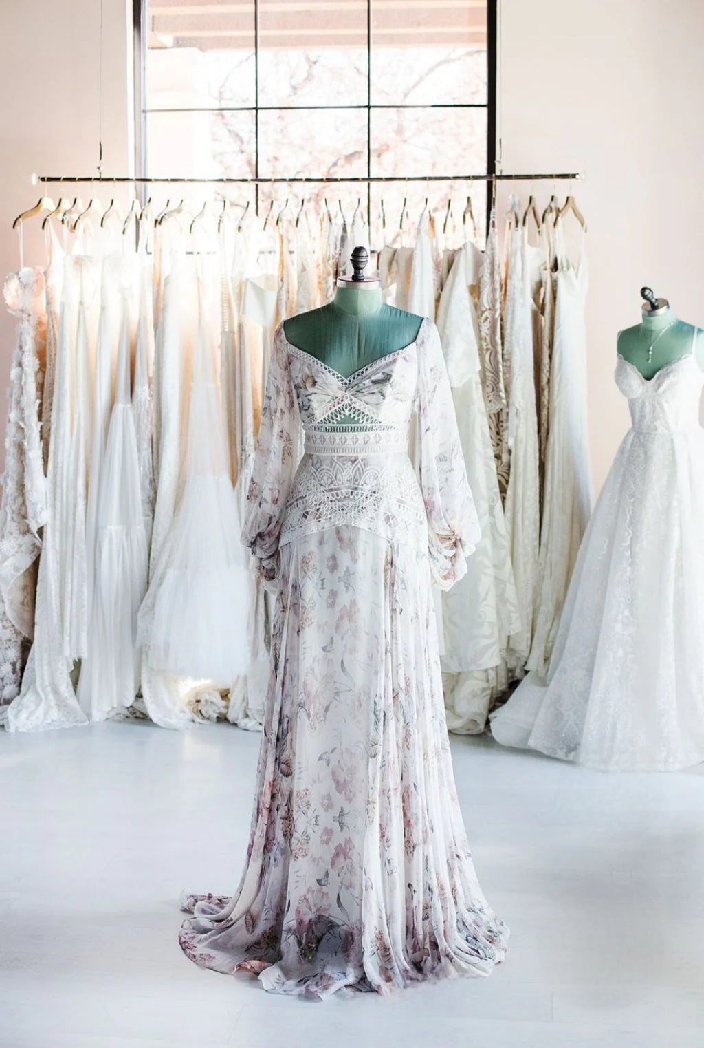 White wedding dress with floral patterns on a mannequin in a store setting.