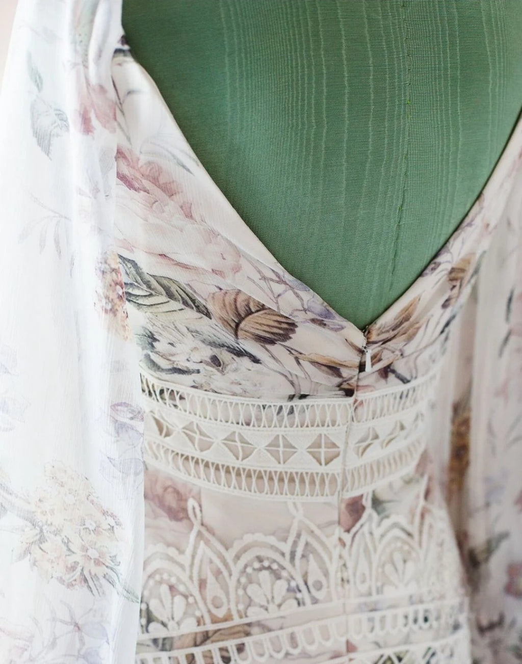 Close-up of a floral dress with lace detailing on a green background