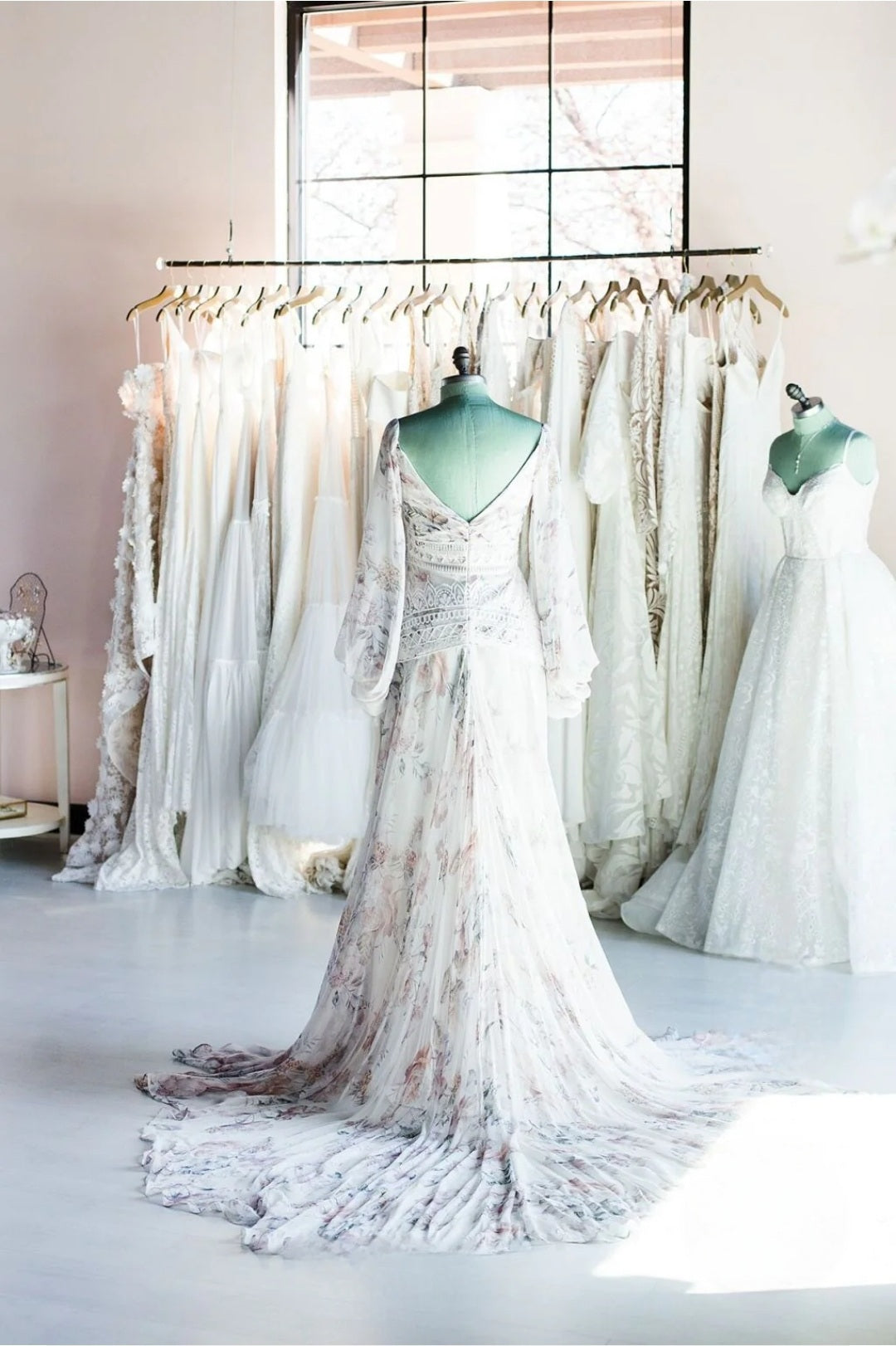 White wedding dress on a mannequin in a room with large windows.