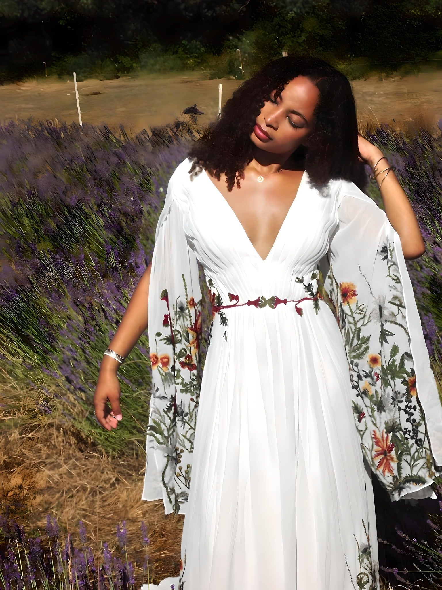 Woman in a white dress with floral embroidery standing in a lavender field