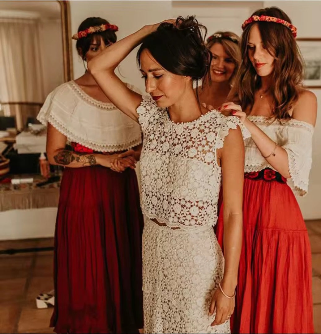 Woman in a white lace dress with three women in red and white dresses adjusting her hair.