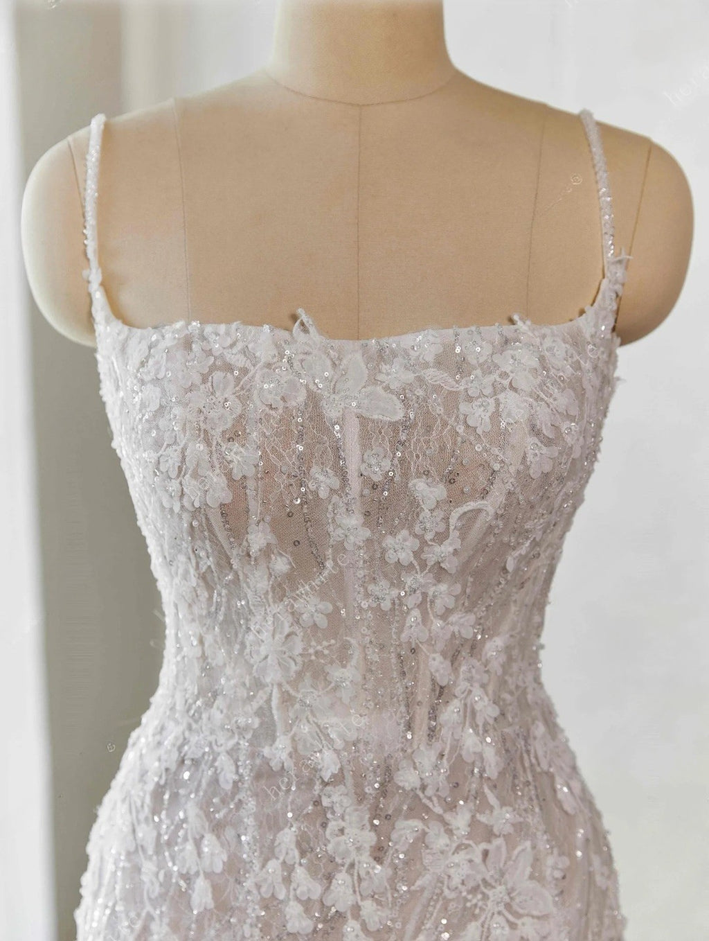Lace wedding dress on a mannequin against a white background