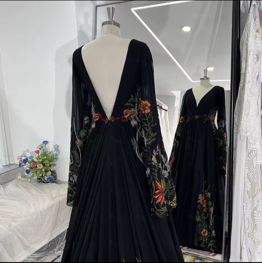 Black dress with floral embroidery on a mannequin in a store setting.