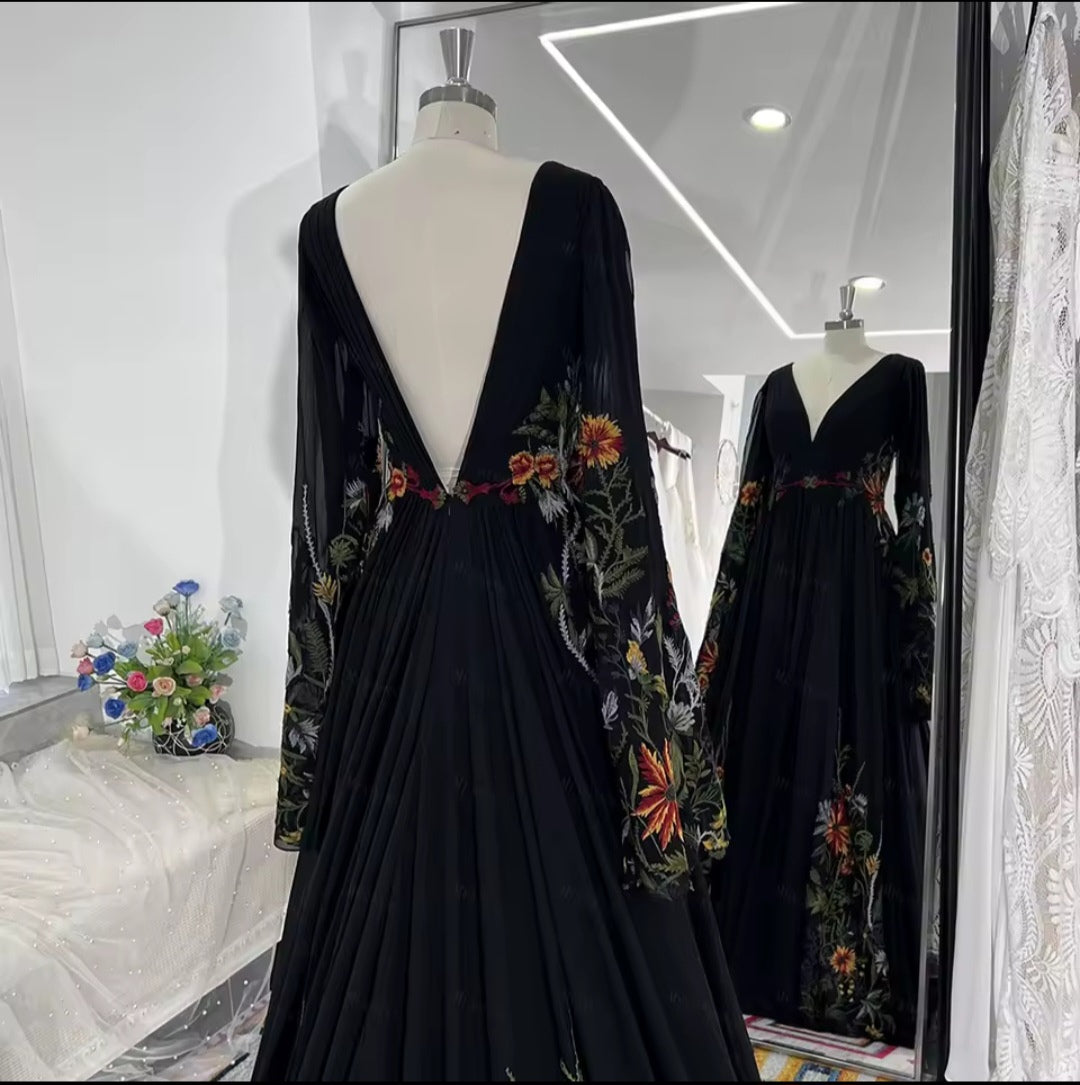 Black dress with floral embroidery on a mannequin in a store setting.