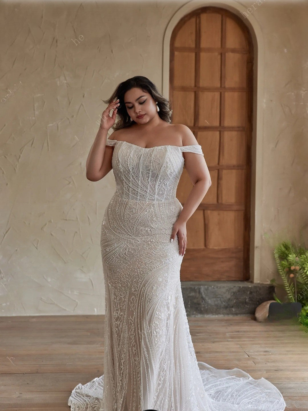 Woman in a white off-shoulder gown standing in front of a wooden door.