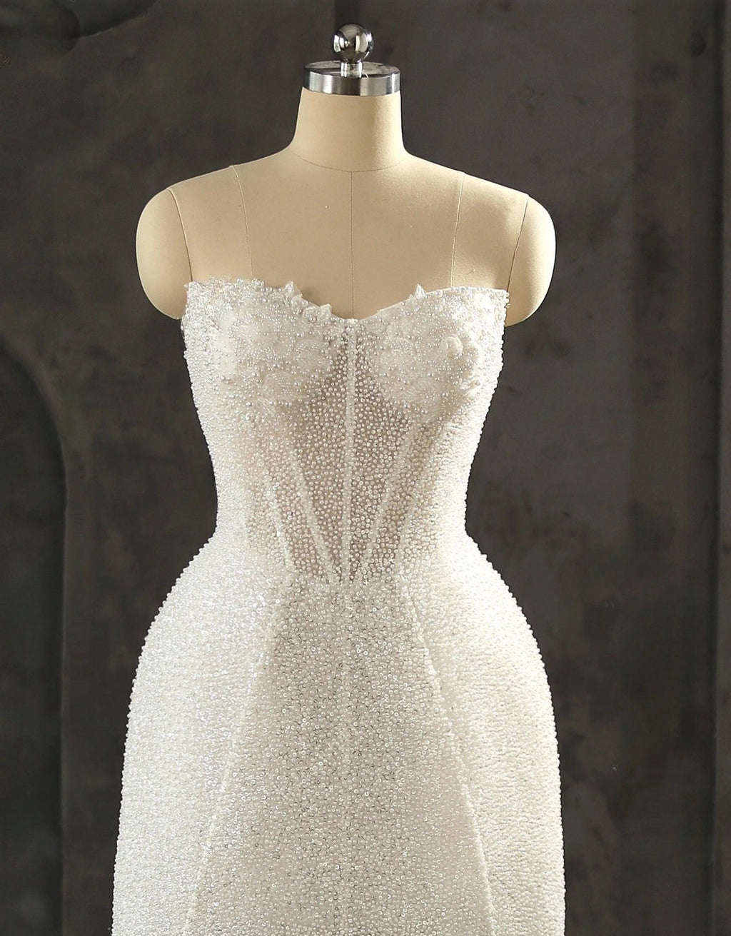 White beaded dress on a mannequin against a dark background