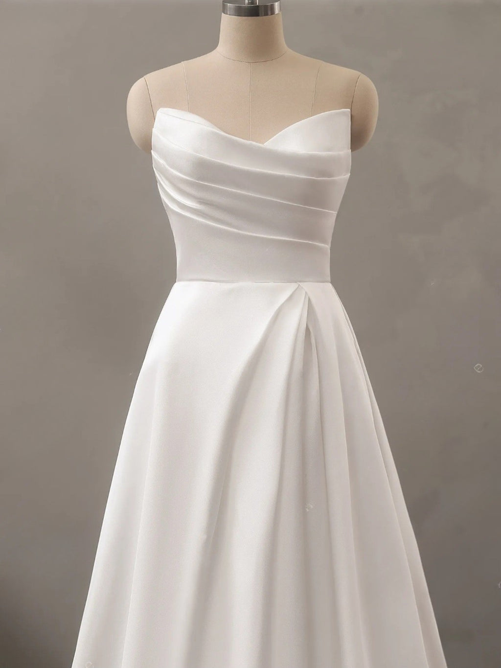 White strapless dress on a mannequin against a plain background