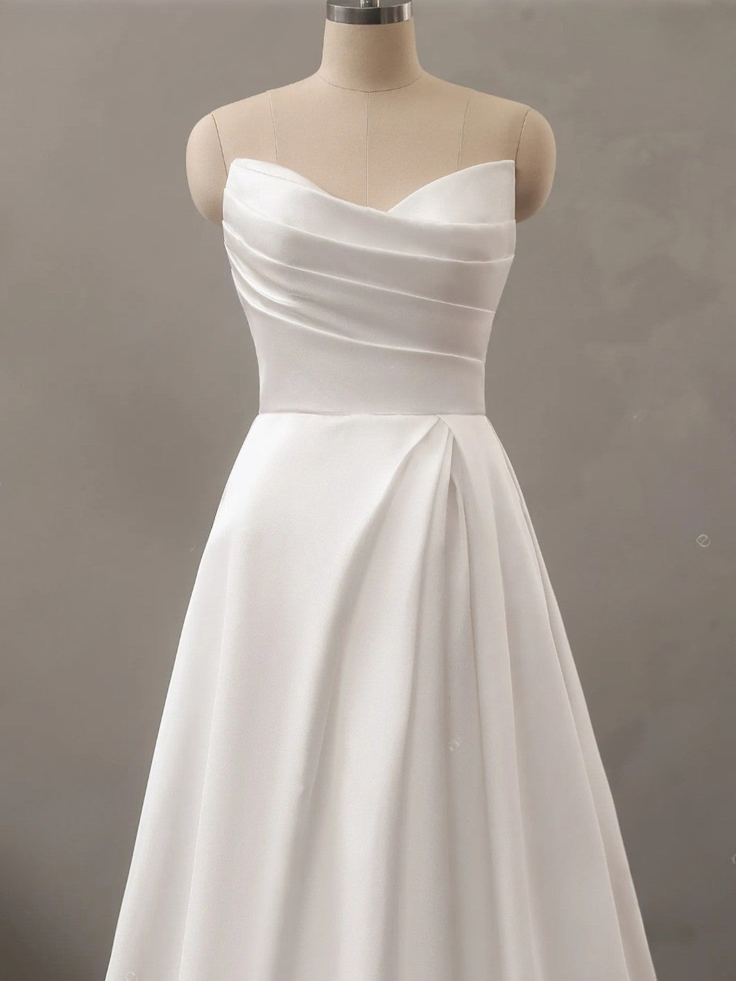 White strapless dress on a mannequin against a plain background