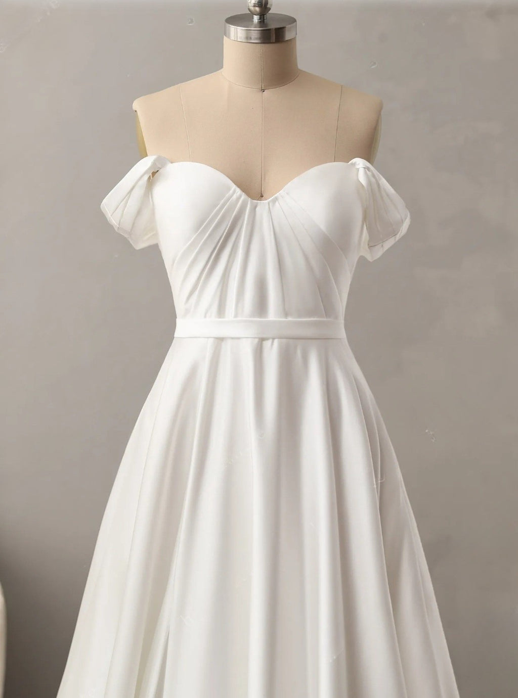 White off-shoulder dress on a mannequin against a plain background