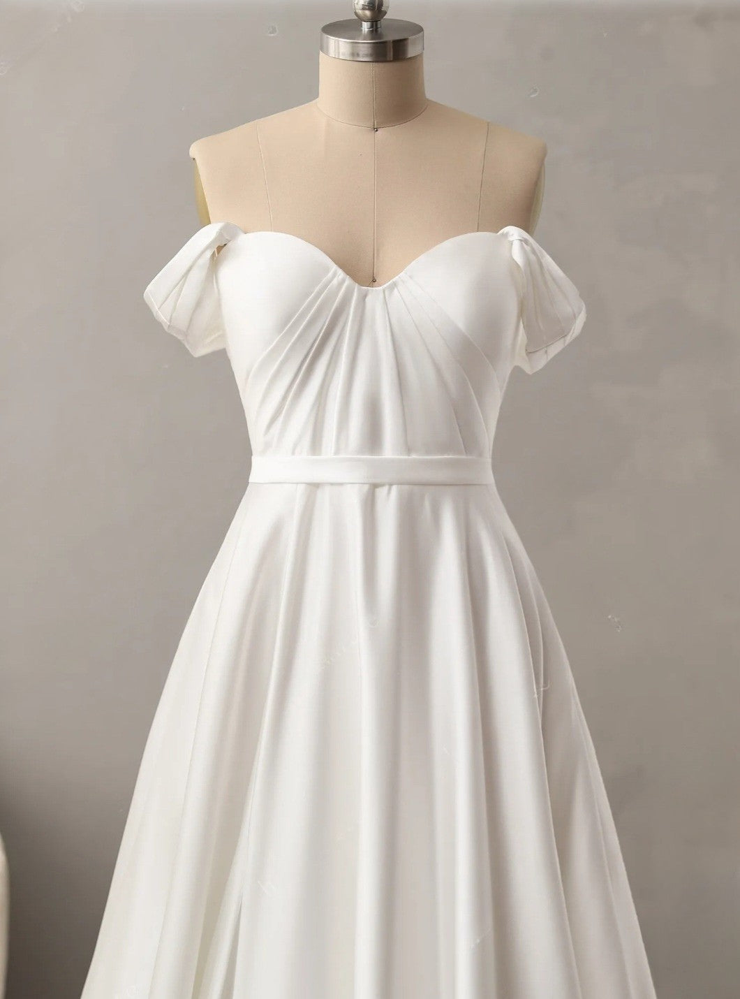 White off-shoulder dress on a mannequin against a plain background
